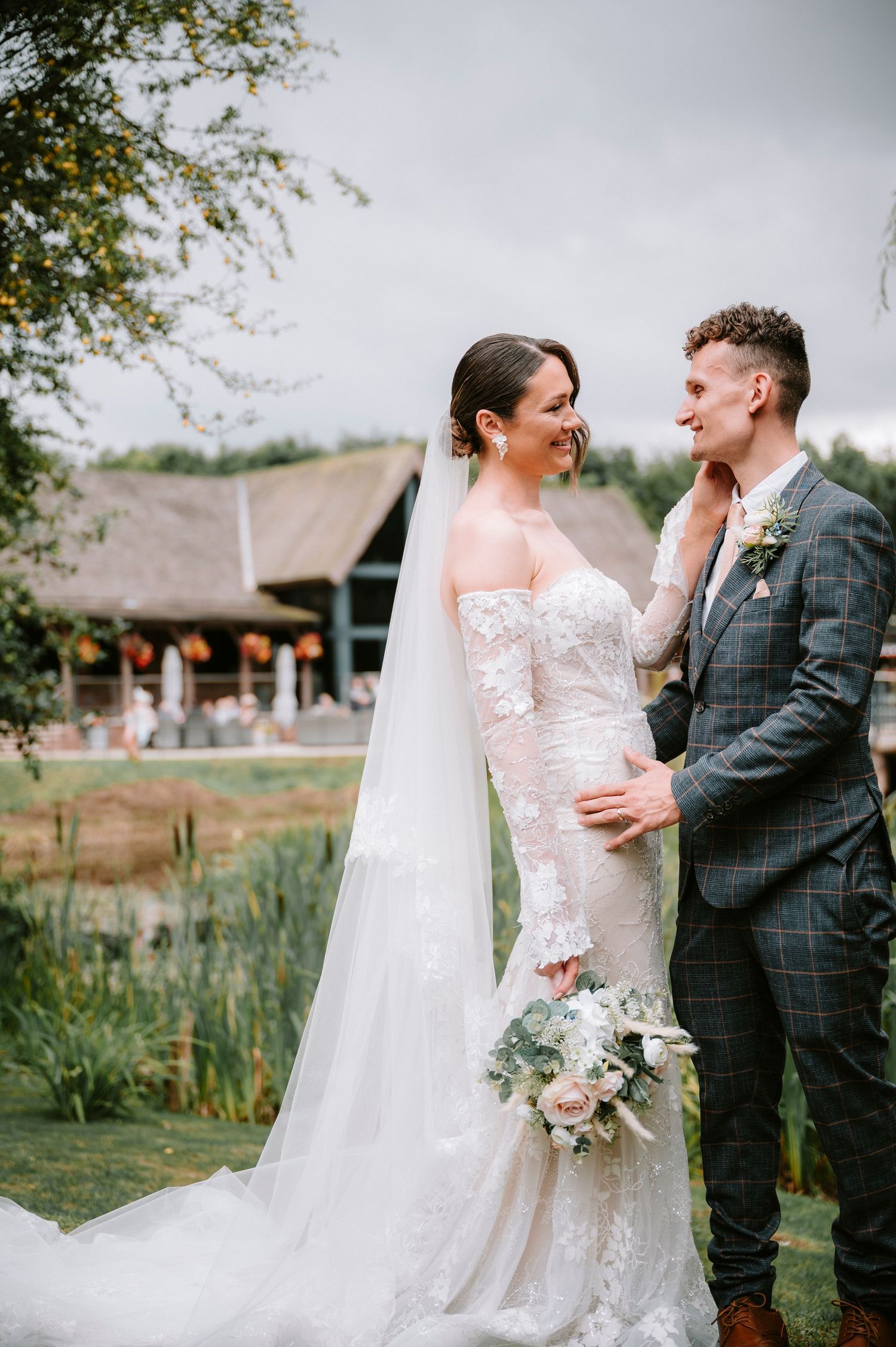 Couple shares intimate moments during outdoor wedding photoshoot with rustic venue in background.