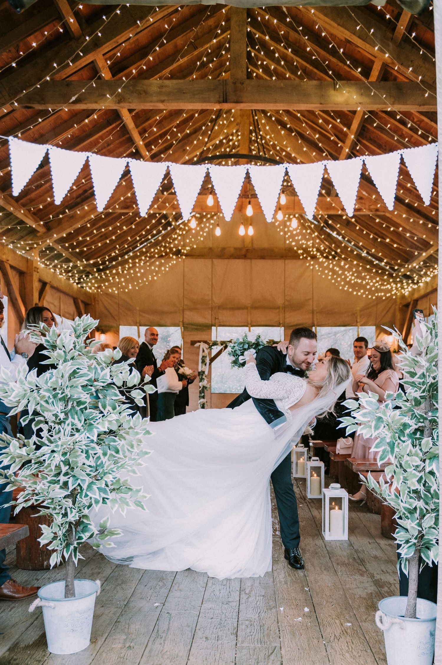 Wedding celebration in a barn venue decorated with twinkling lights and white banners.