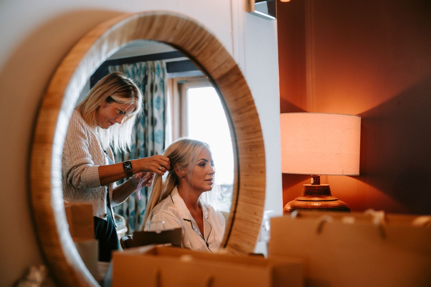 Getting ready moments captured through mirror reflections in warm lighting.