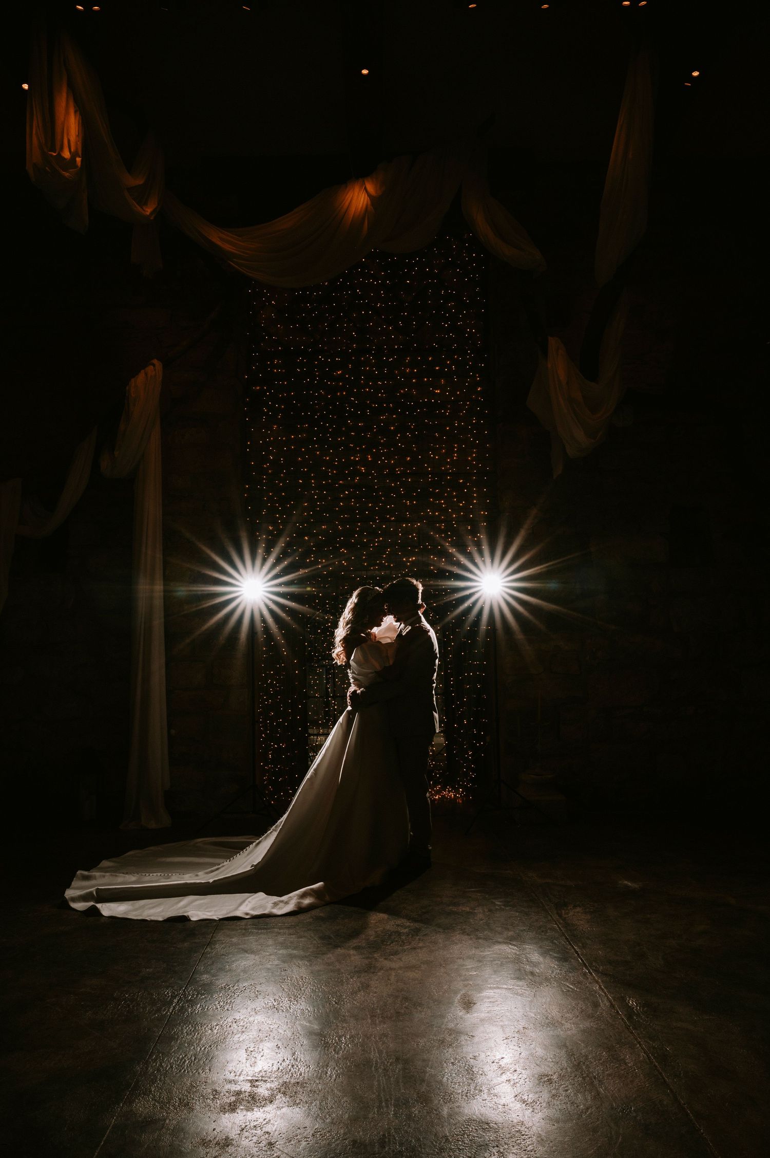 Dramatic dance floor scene with spotlights illuminating a couple in formal attire during their first dance.