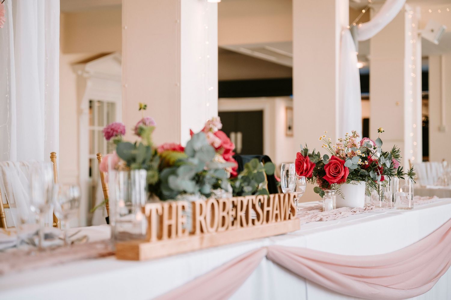 Elegant wedding reception setup with white columns and draped fabric decor.