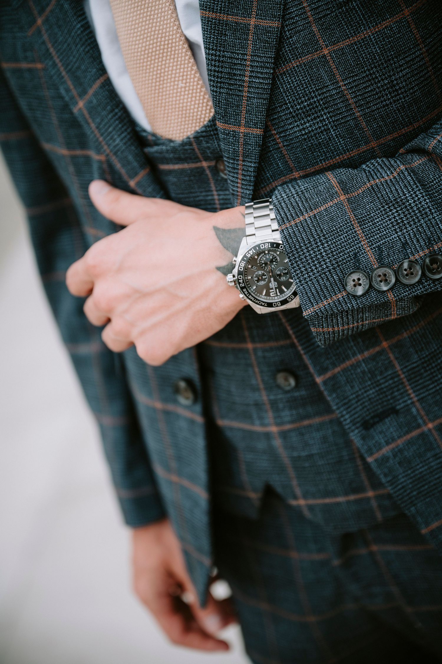 Detail shots of a plaid suit jacket and silver watch accessories.