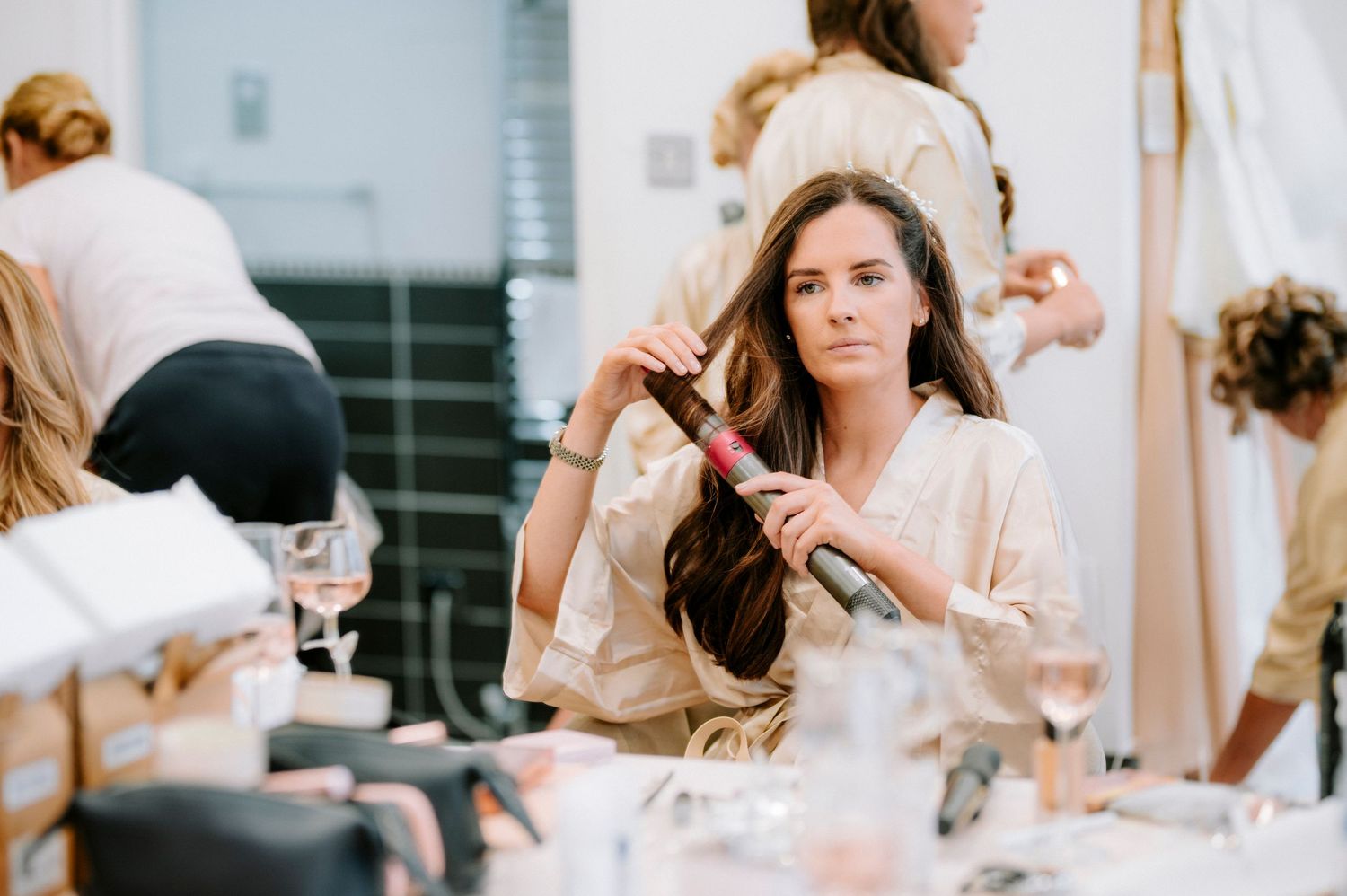 A group getting ready in matching white satin robes during wedding preparations.