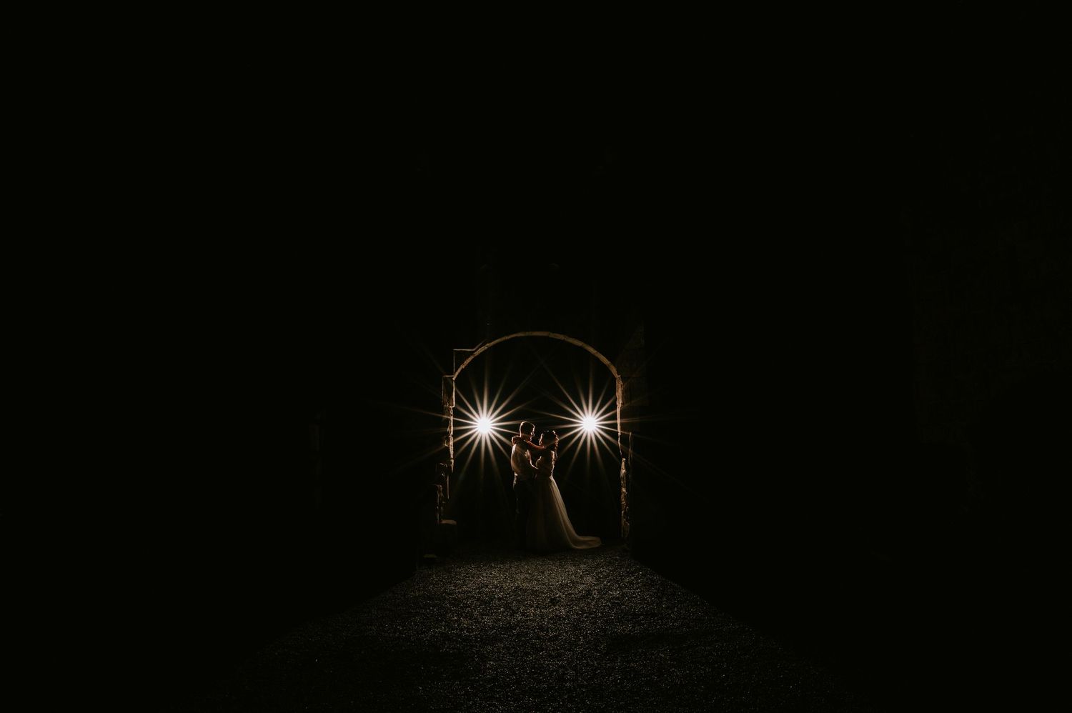 Two bright lights shine through a dark tunnel entrance creating an eerie atmospheric scene.