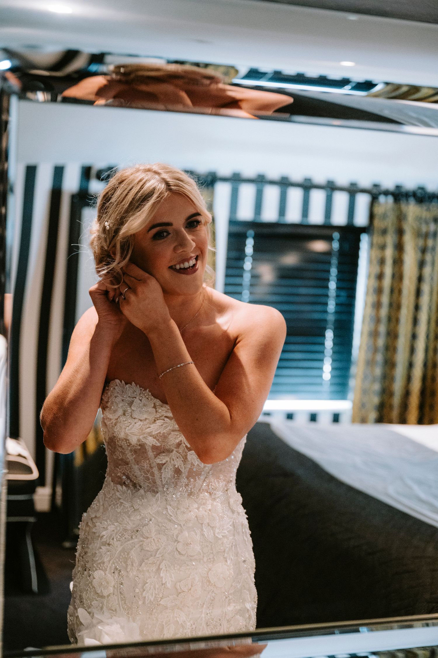 Candid moments of laughter and joy captured in a bridal suite with a black tufted couch.