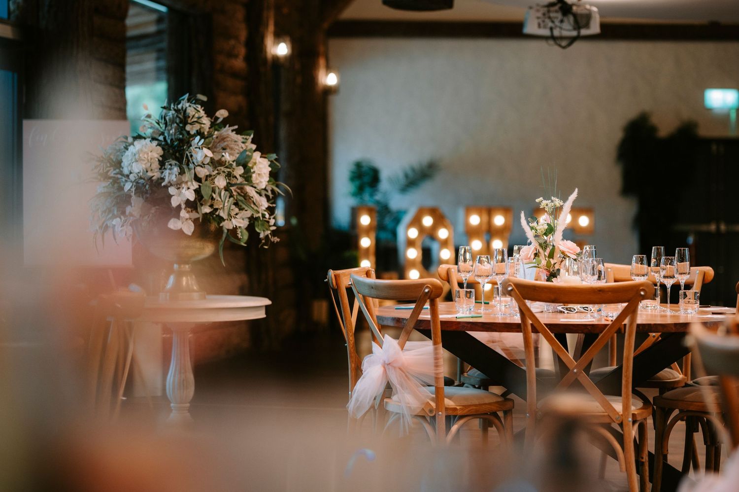 Elegant wedding reception setup with floral centerpieces and wooden cross-back chairs.