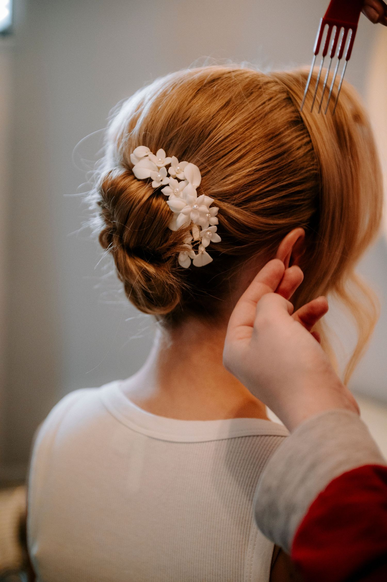 Close-up of delicate floral hair accessories being placed in an updo hairstyle.