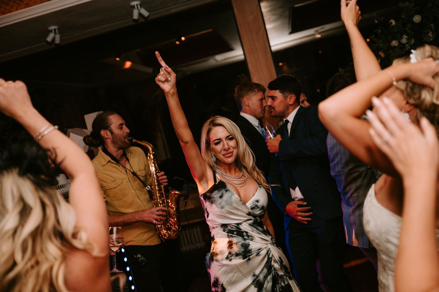 Wedding reception dance party with guests celebrating and dancing under indoor lighting.