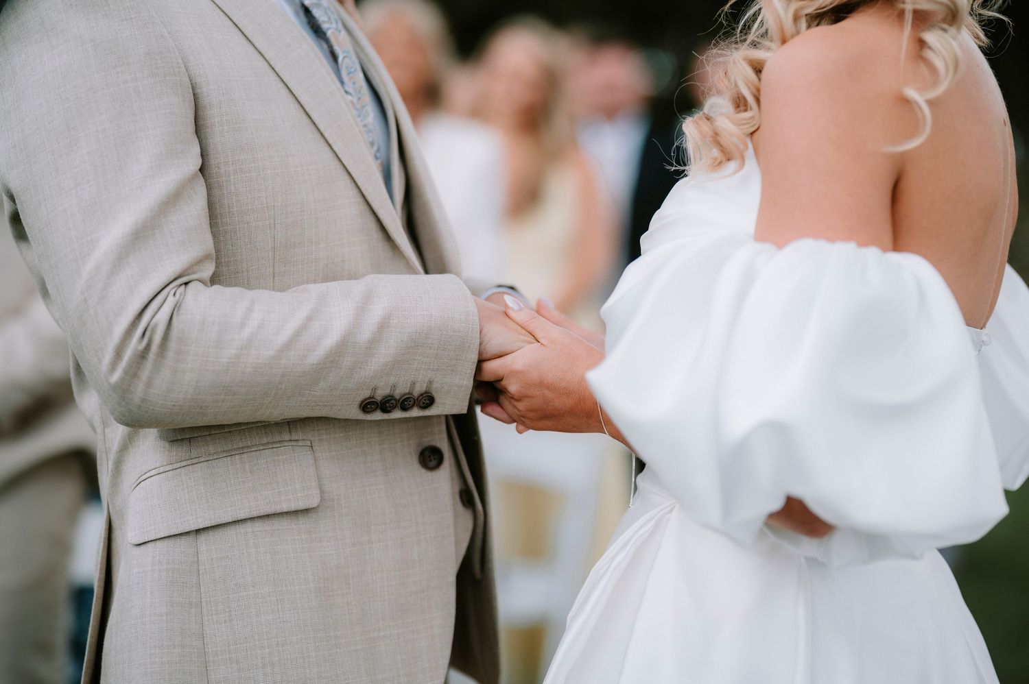 Couple in formal attire signing marriage documents during an outdoor wedding ceremony.