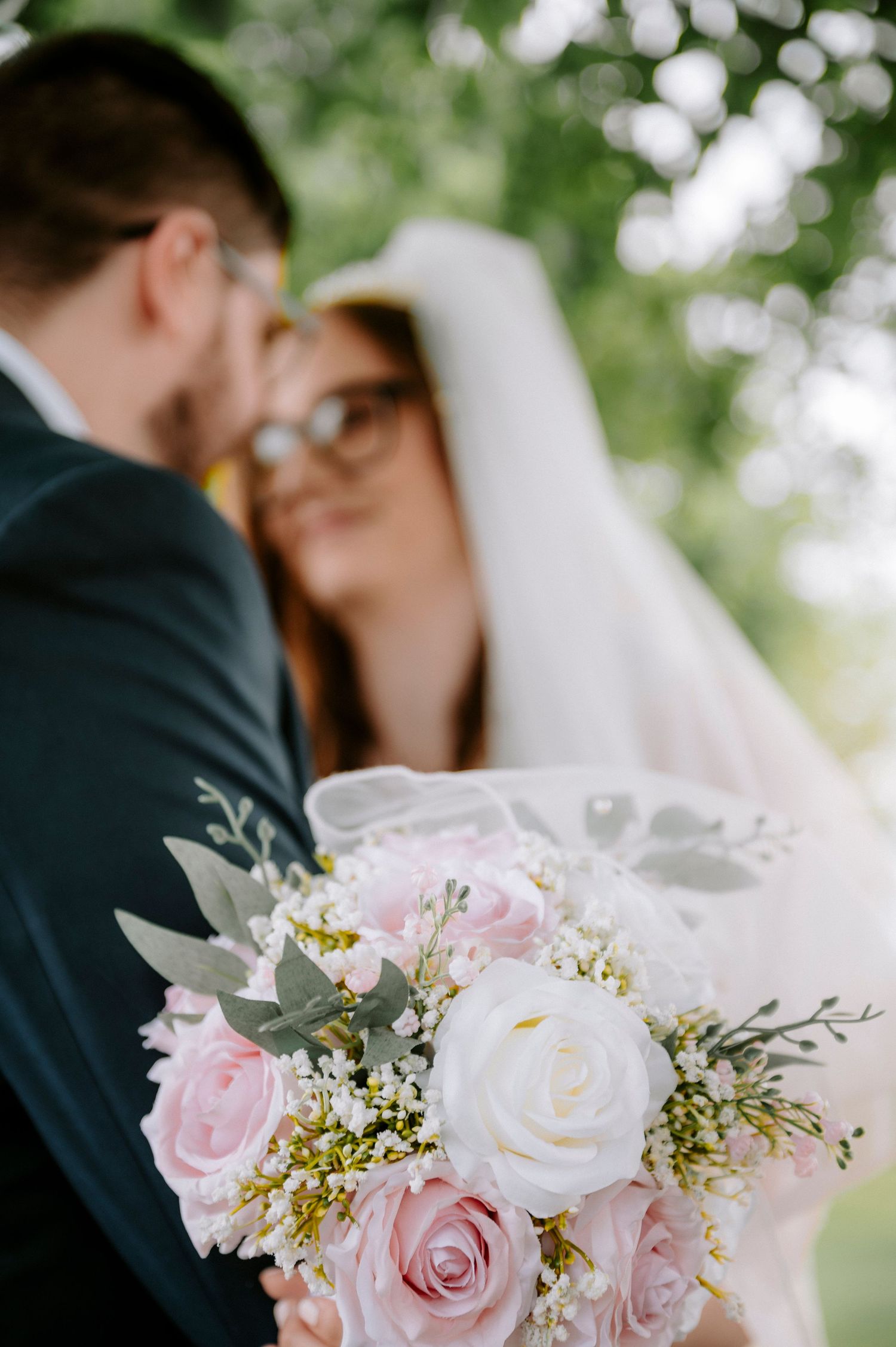 Delicate pink and white rose wedding bouquet with baby's breath and greenery.