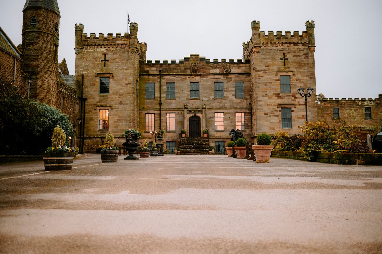 Historic stone castle with crenellated walls and towers under overcast sky.