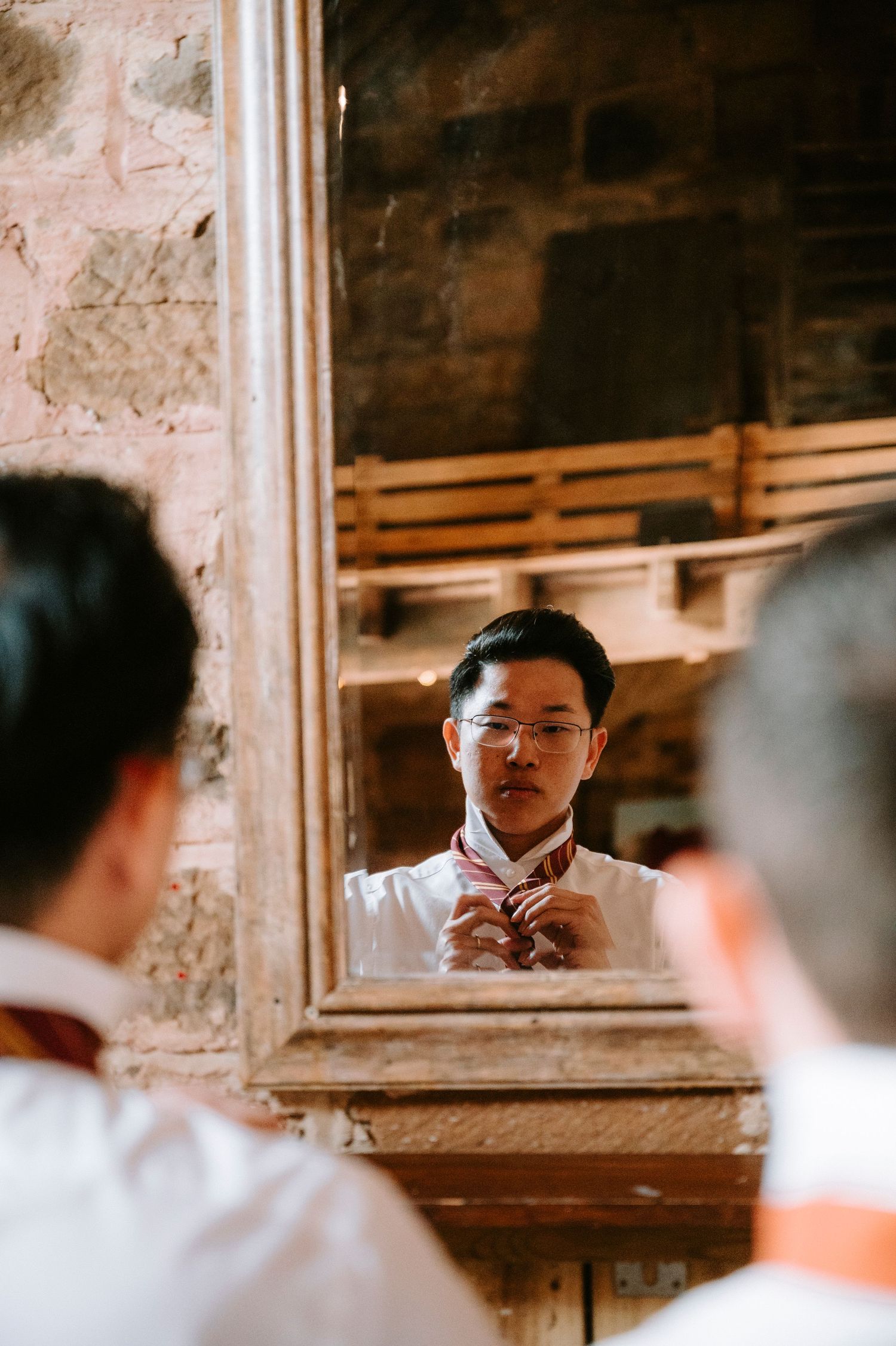 A reflection in a mirror shows someone adjusting a bowtie while getting ready.