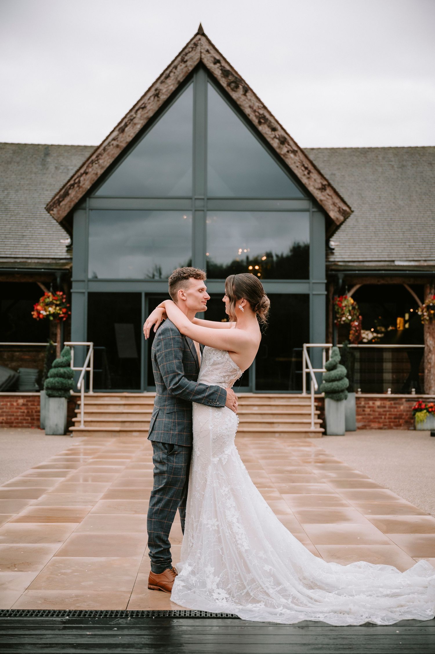 Modern wedding venue exterior featuring A-frame architecture with glass panels and brick details.