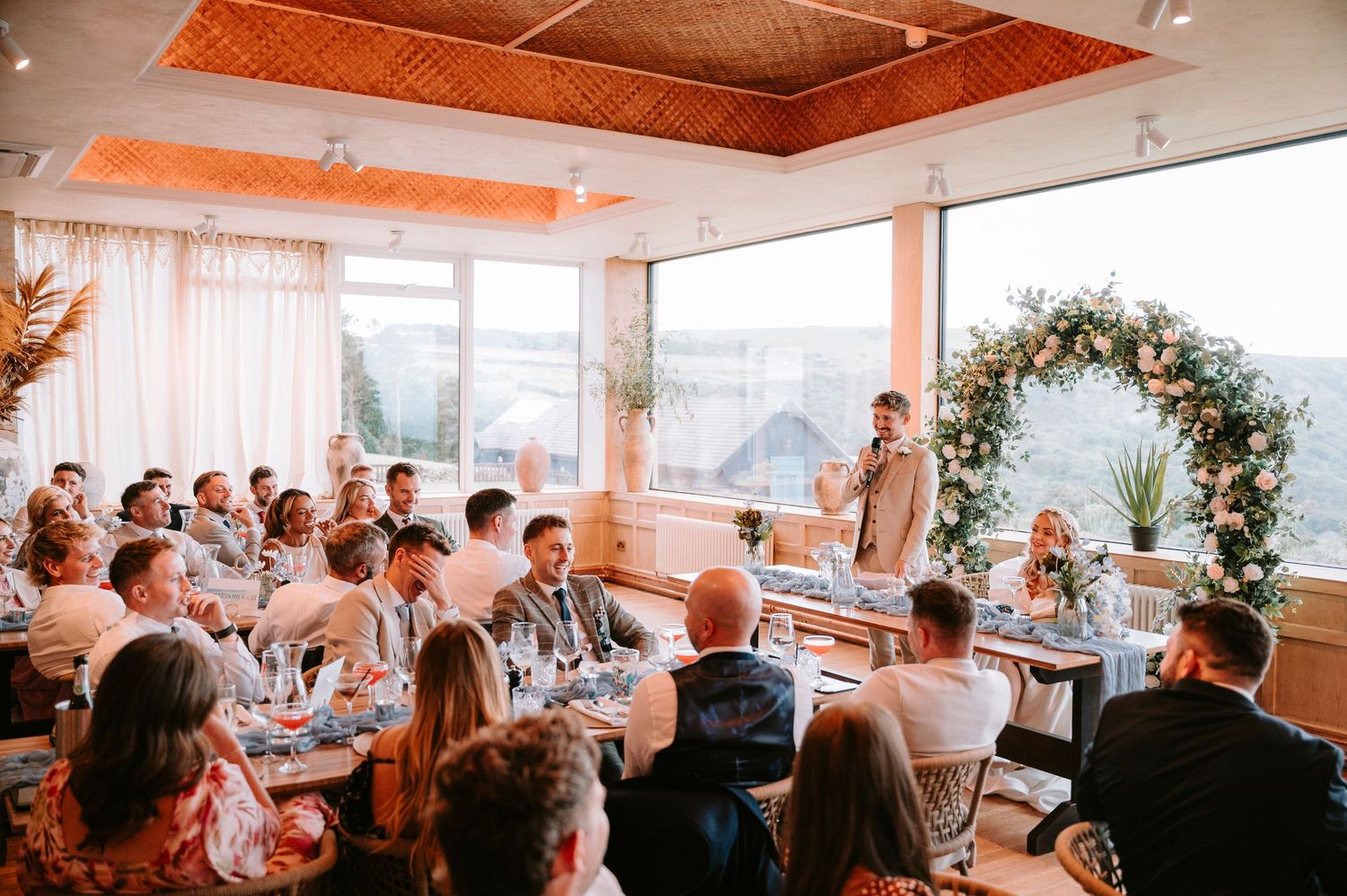 Wedding reception venue with warm lighting and wooden ceiling beams creates an inviting atmosphere.