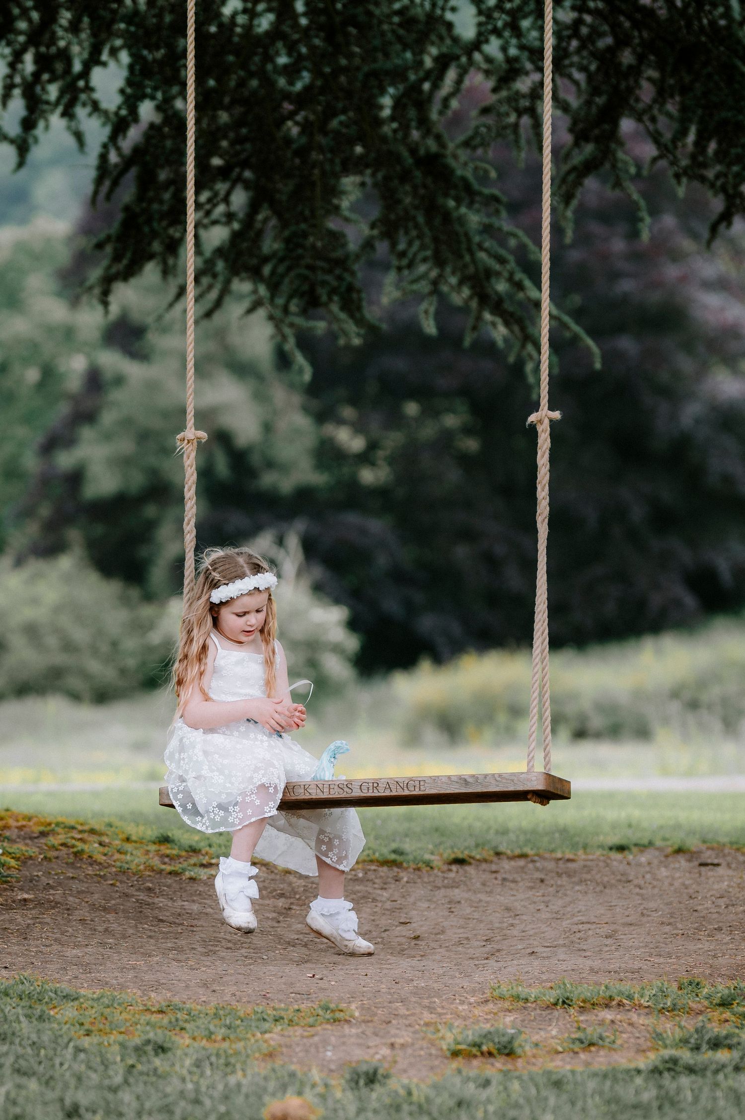 Charming wooden tree swing decorated for a rustic outdoor wedding.