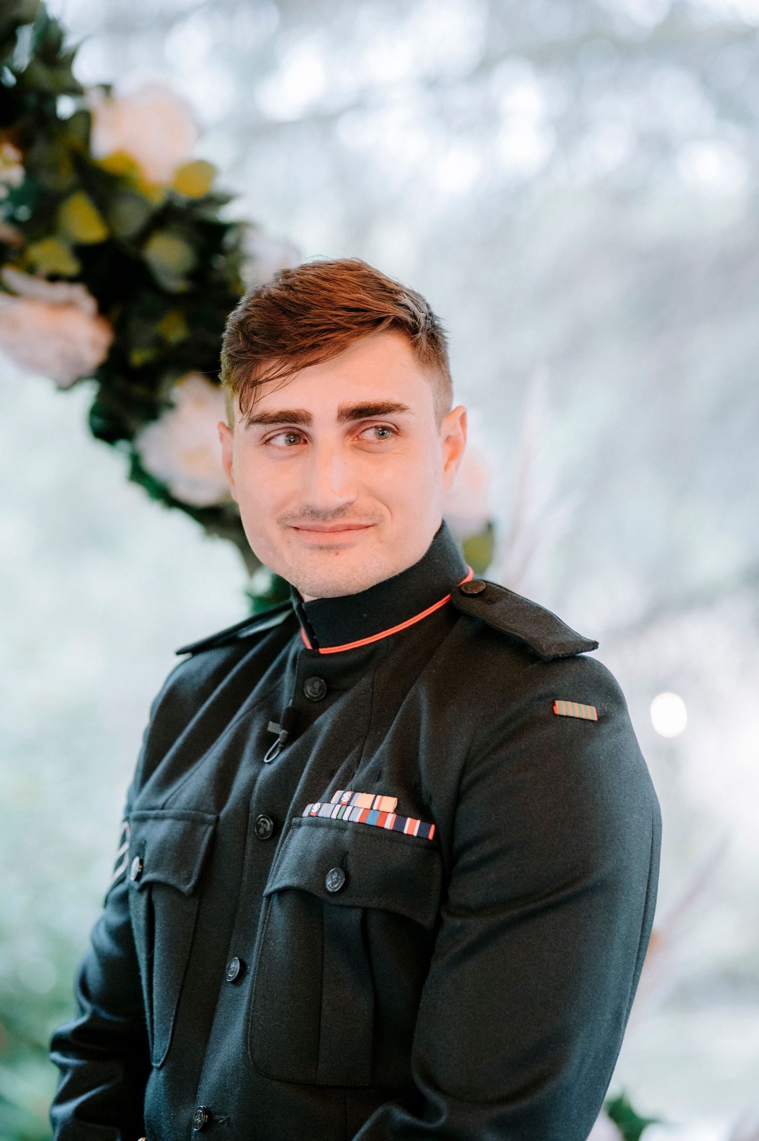 Person in military dress uniform poses outdoors against a soft bokeh background.
