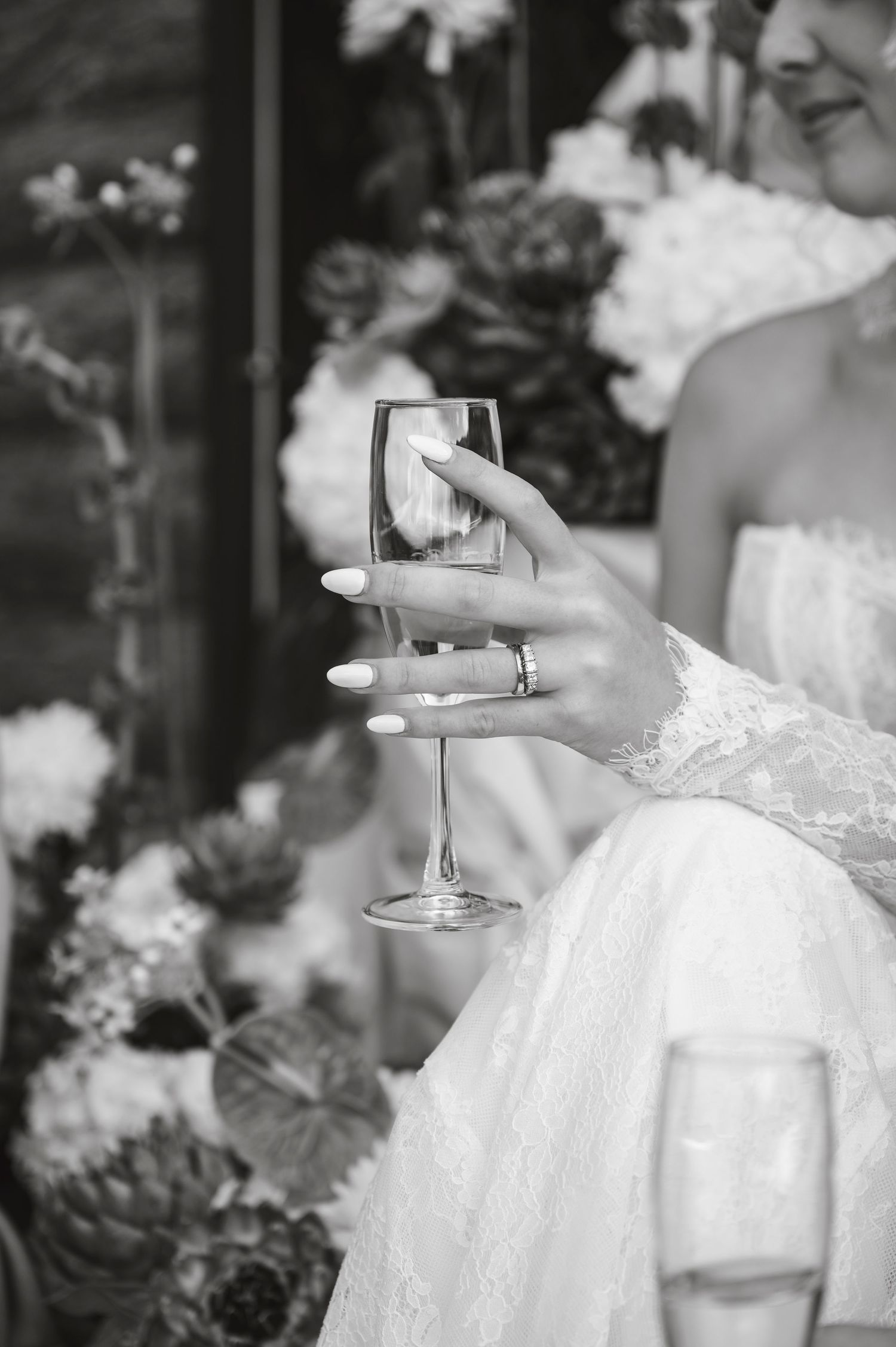 Close-up details of a white lace wedding dress and champagne glass during a celebration.