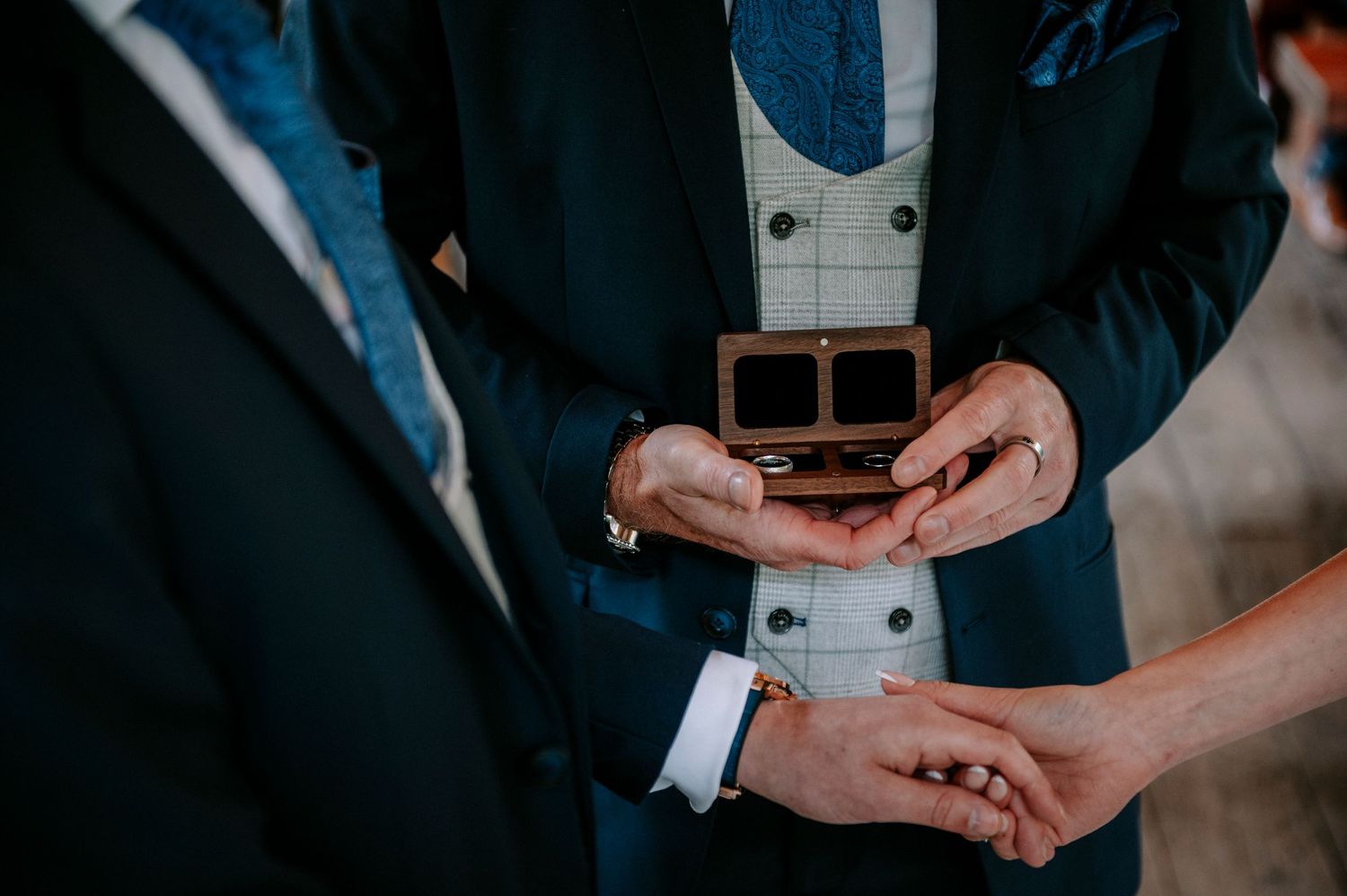 Detail shot of hands exchanging rings during wedding ceremony.