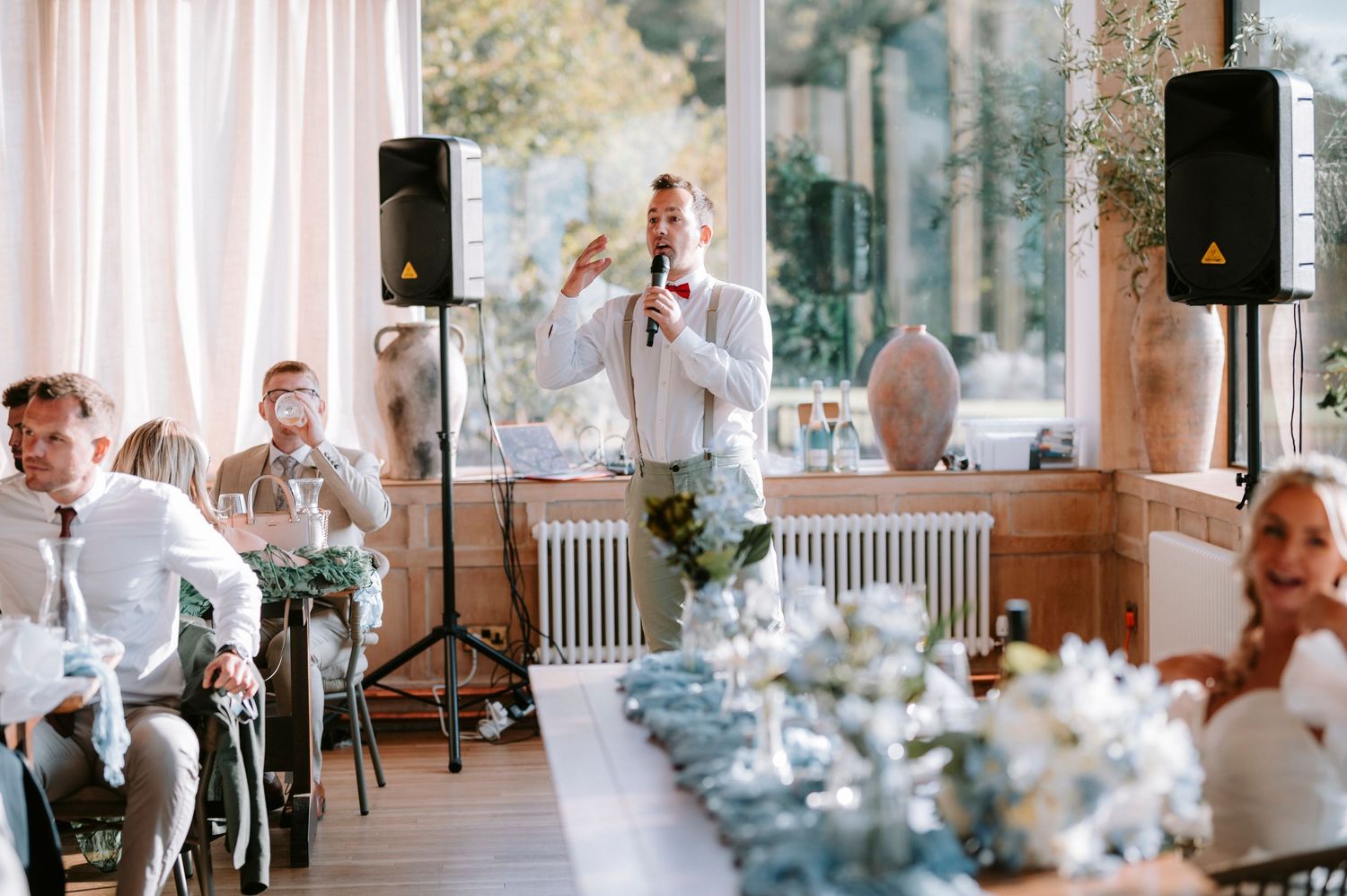 Elegant wedding reception setup with blue and white table settings in a bright indoor venue.
