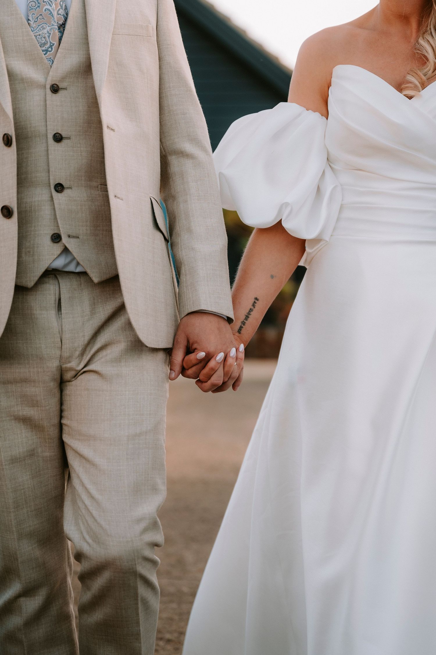 Close-up details of wedding attire showing beige suits and white bridal gown during ceremony.