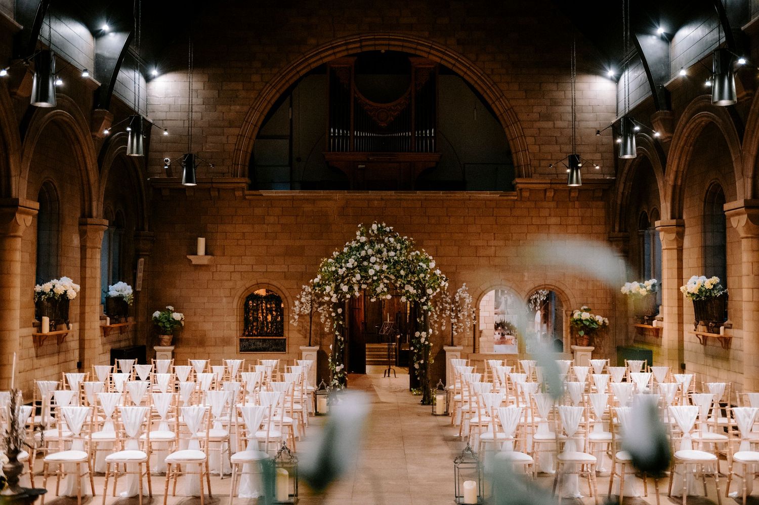 Rustic indoor wedding venue with brick walls and romantic lighting for ceremony setup.