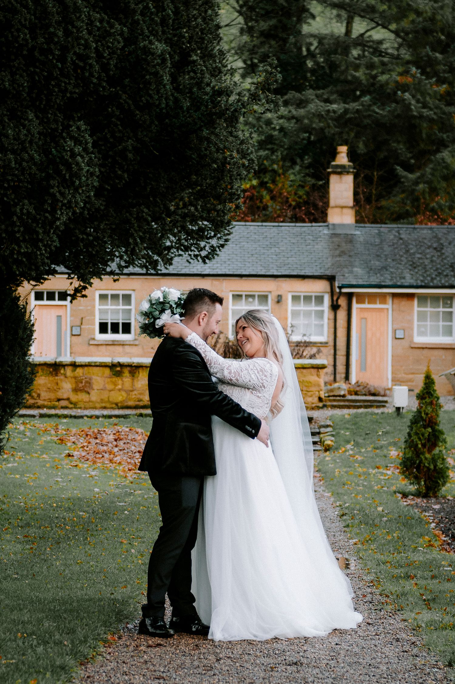 A tender moment between newlyweds in front of a quaint countryside cottage.