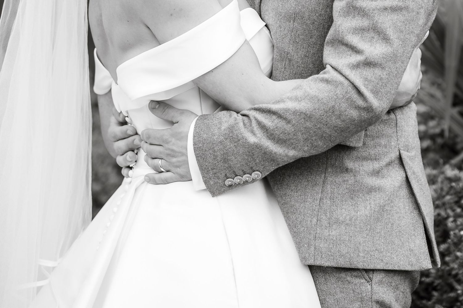 Wedding couple embracing in elegant white dress and light gray suit.