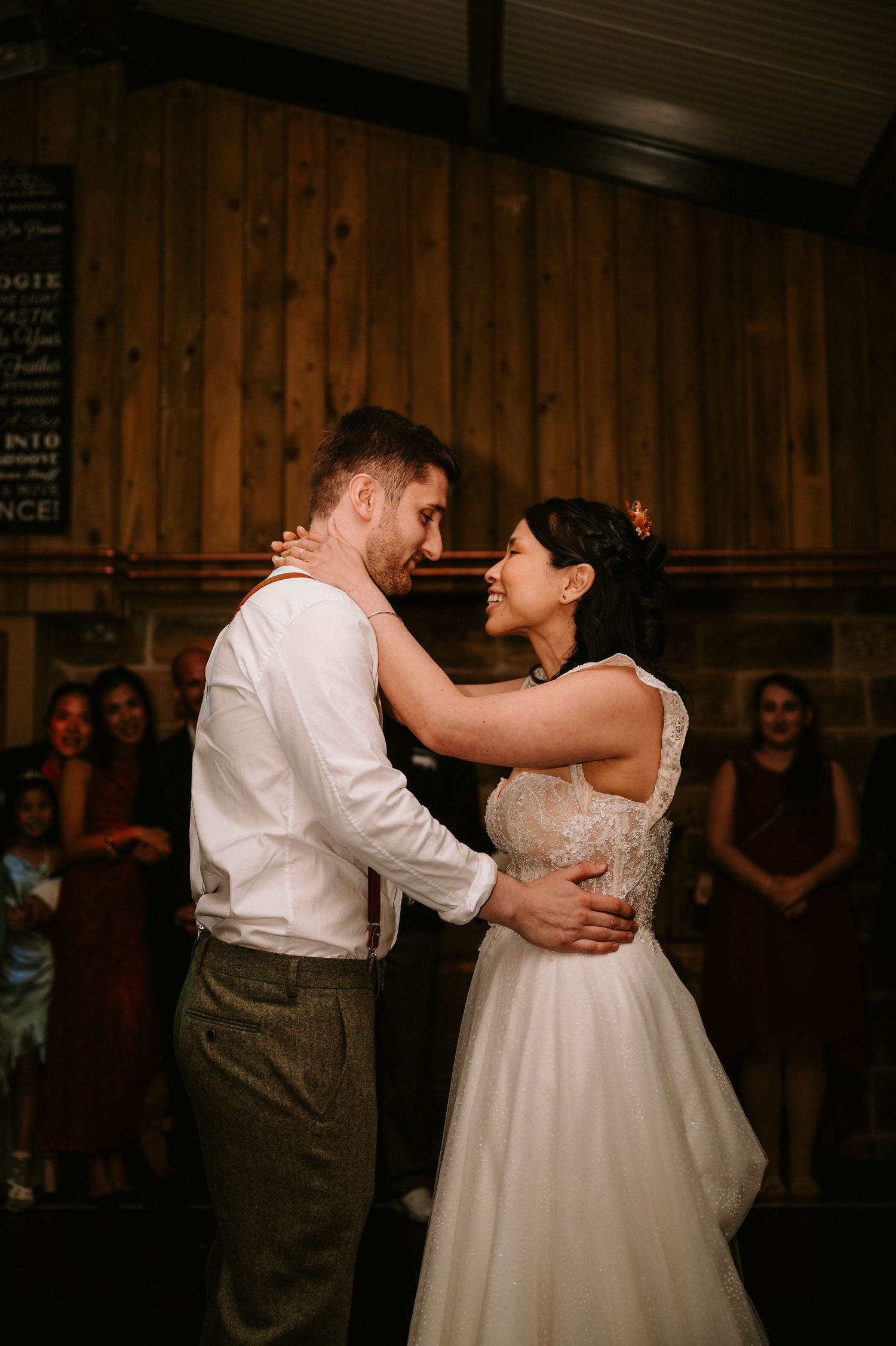 First dance in rustic wooden venue with warm ambient lighting.