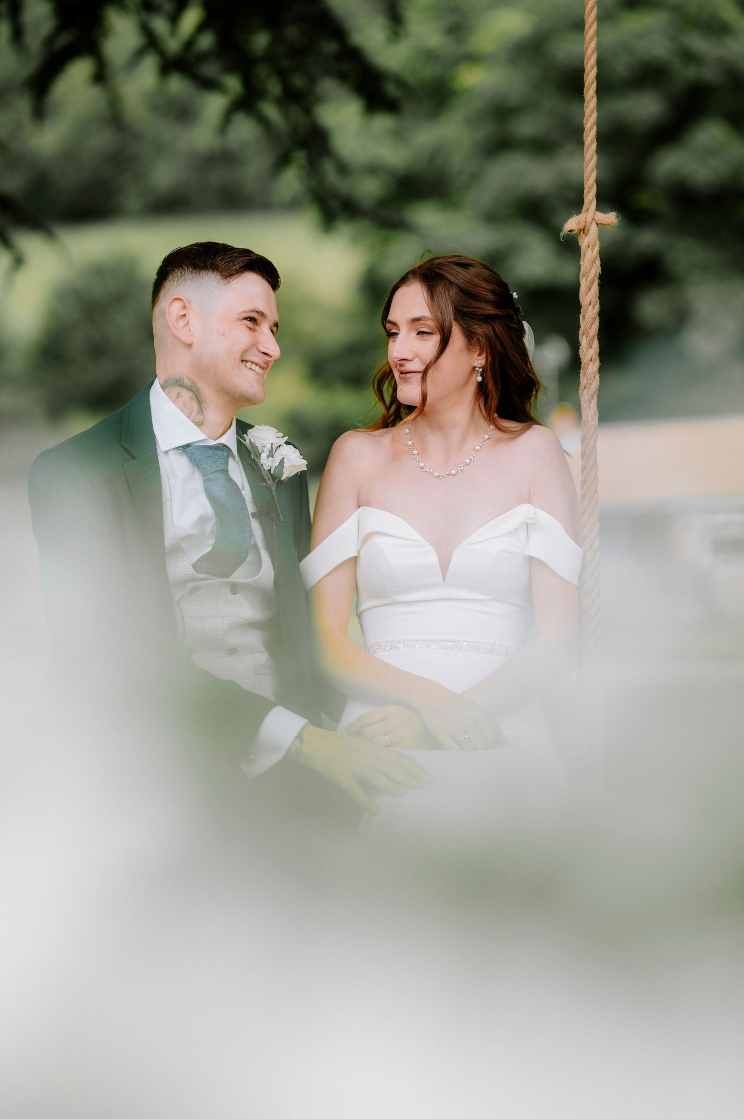 Soft-focus wedding portraits showing tender moments between newlyweds on a garden swing.