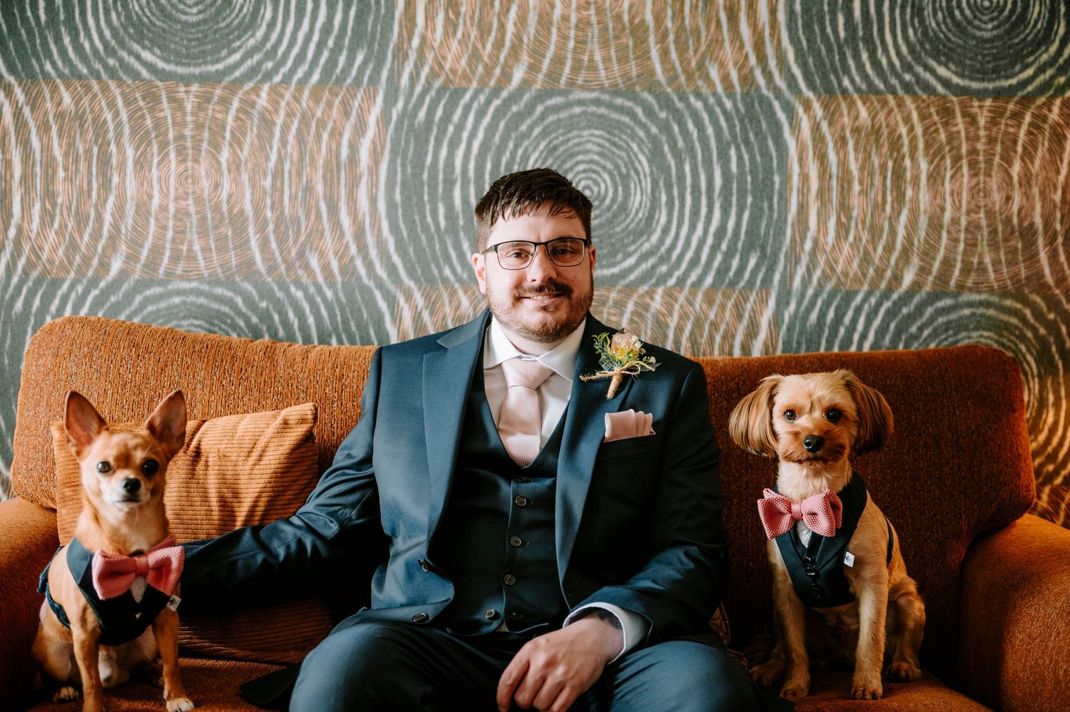 Wedding party members pose on brown leather couch in formal attire.