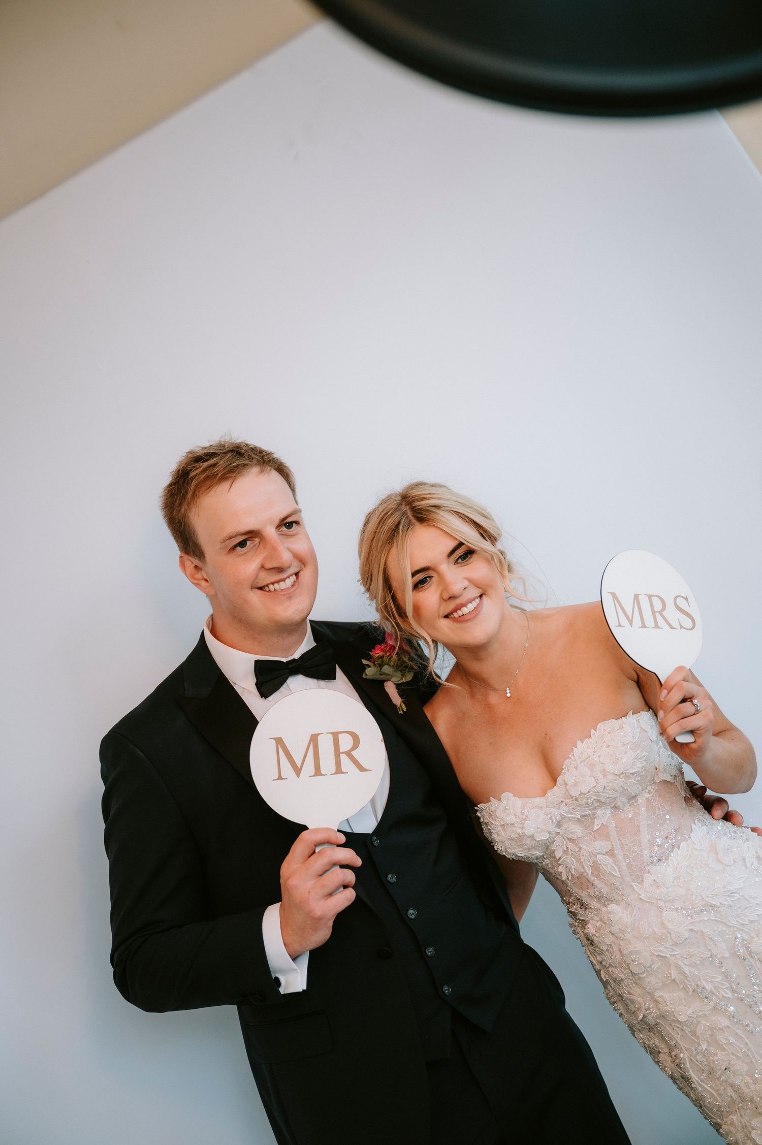 Playful couple holding Mr and Mrs signs against white backdrop.