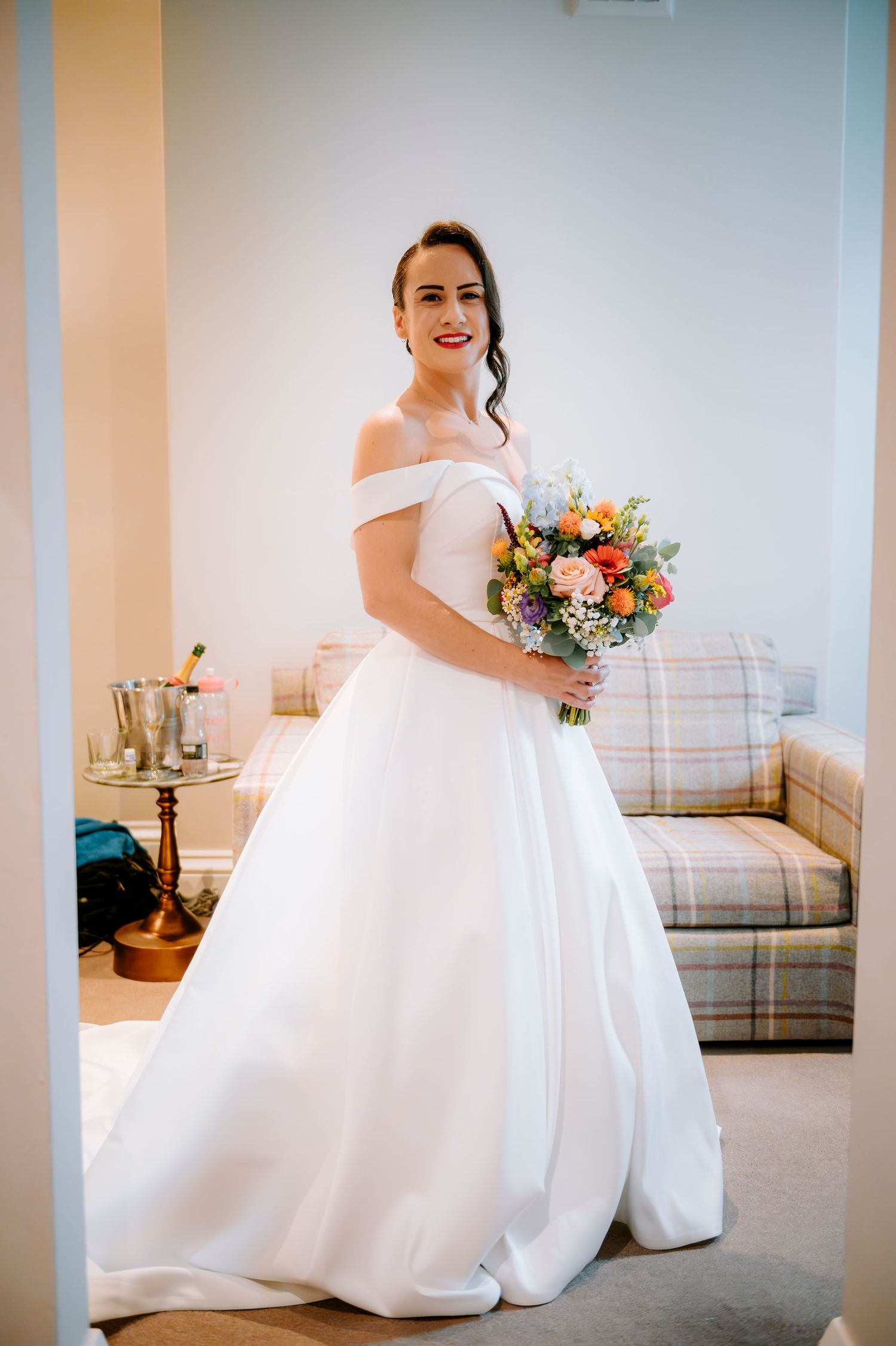 Full-length view of a stunning white ball gown wedding dress with off-shoulder neckline and colorful bouquet.