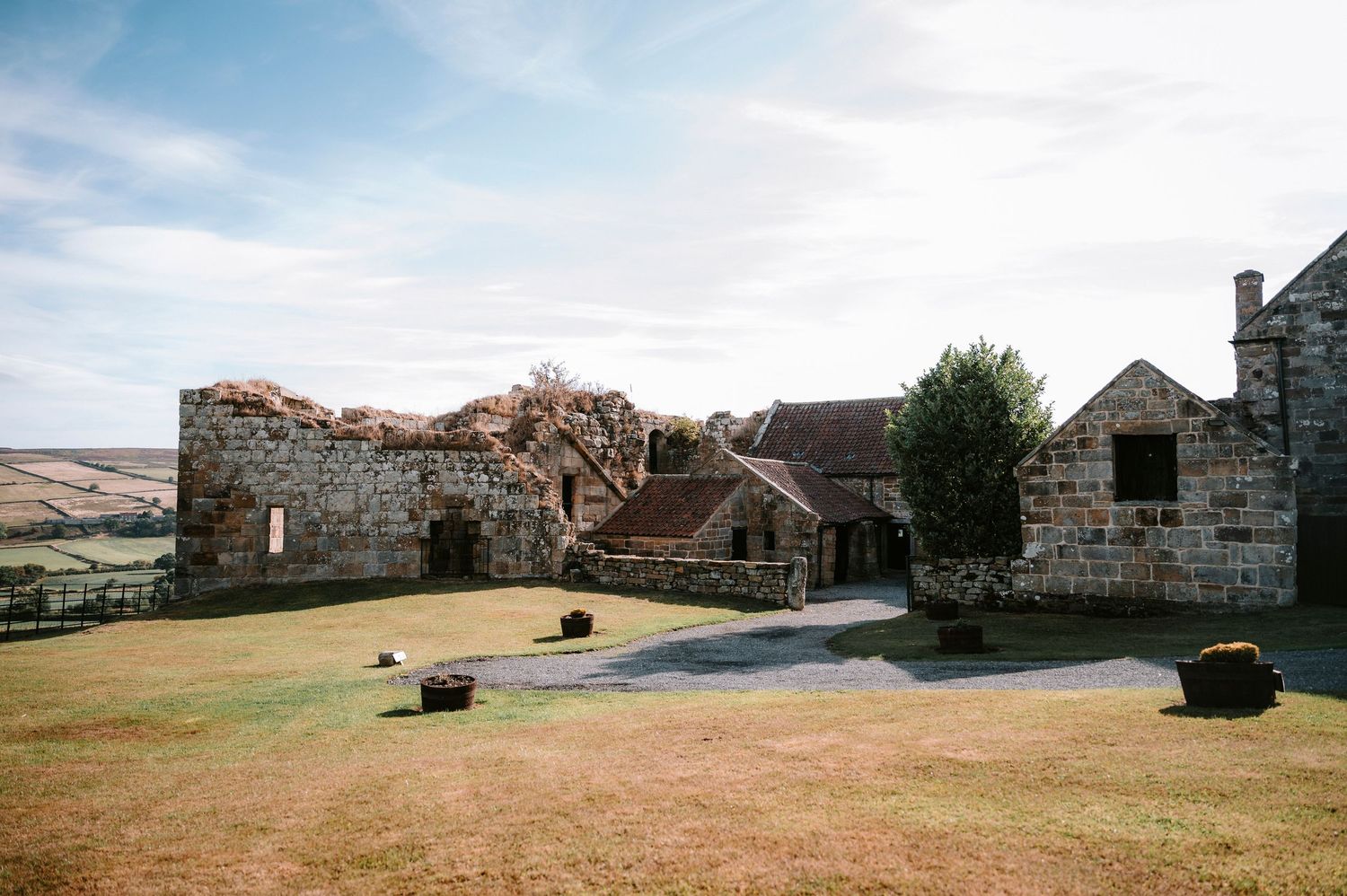 Panoramic view of rustic stone buildings and rolling countryside hills under a cloudy sky.