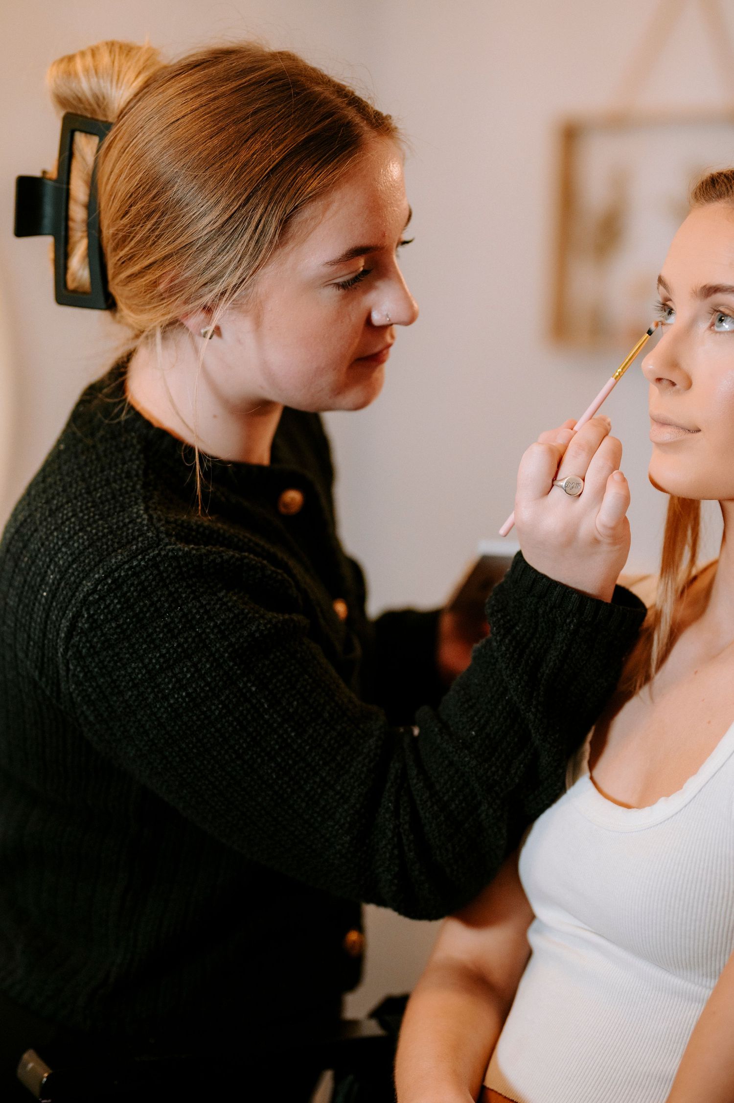 Makeup artist applying cosmetics in a bright, minimalist setting.