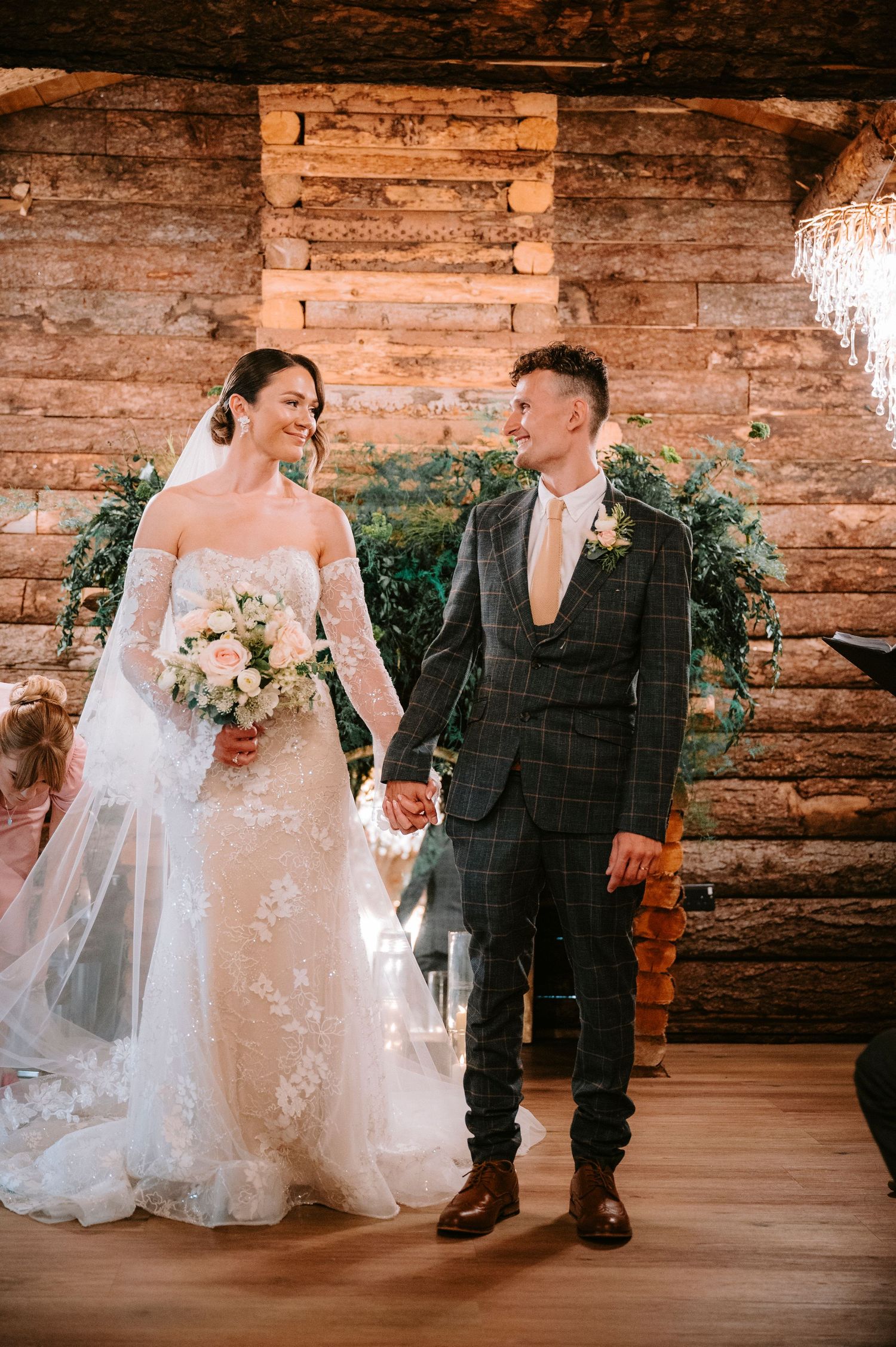 Wedding couple shares intimate moments against rustic wooden wall backdrop at indoor venue.