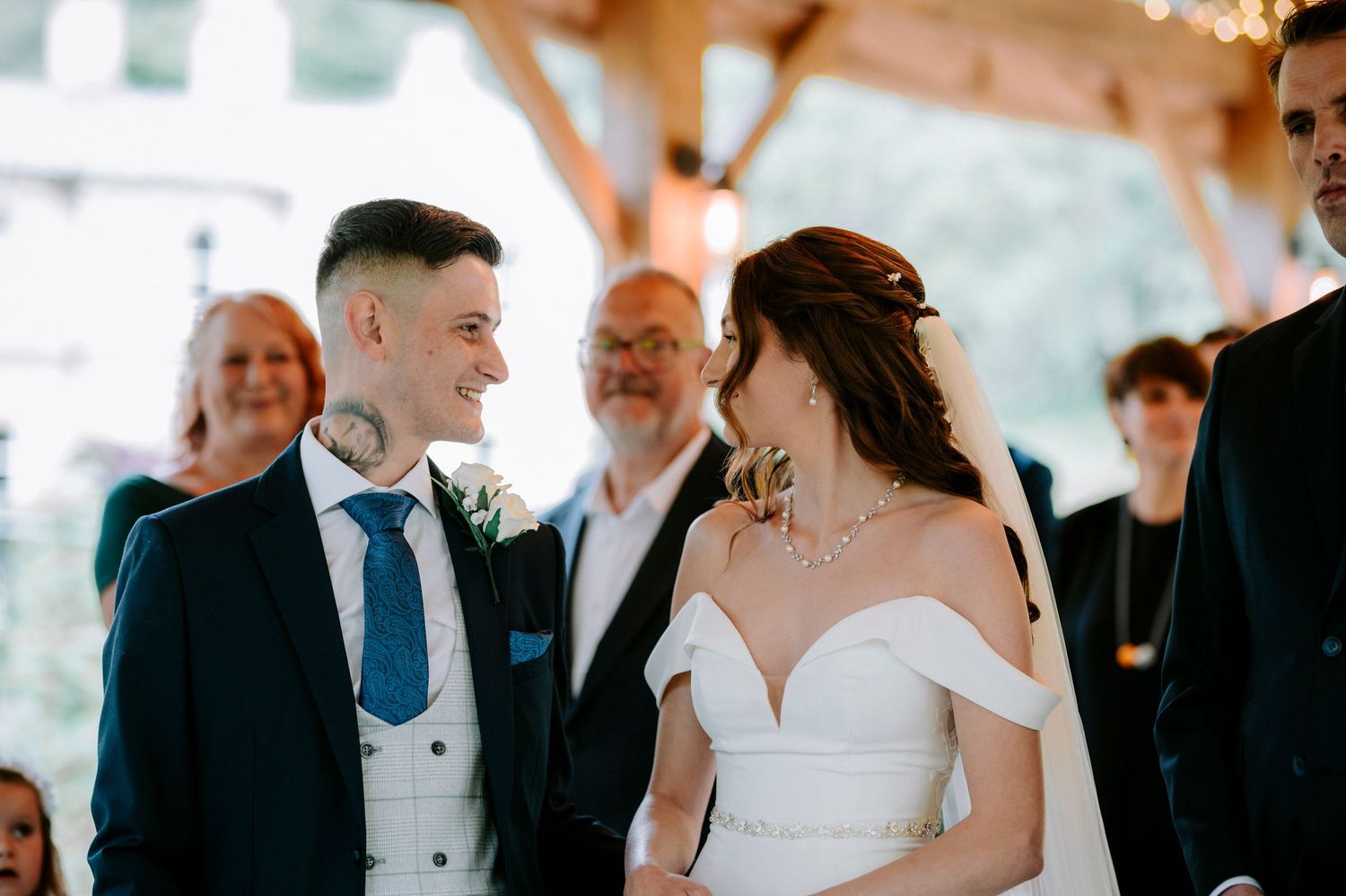 Wedding celebration under wooden beams with string lights and formal attire.