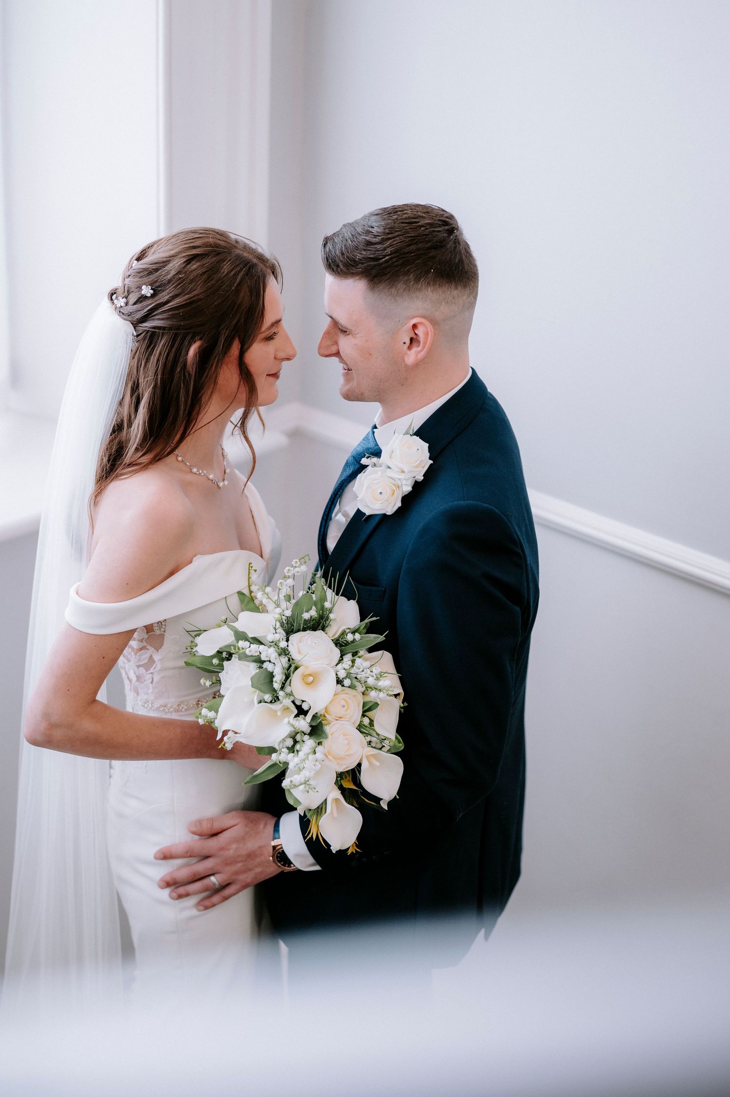 Intimate wedding portraits showing tender moments between newlyweds with white bouquet.
