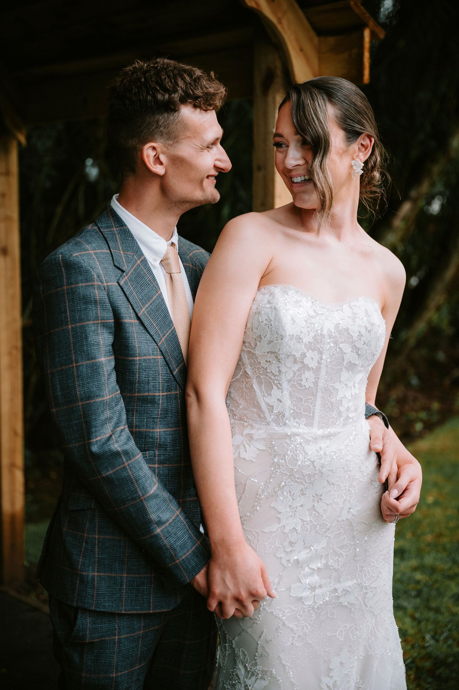 Close-up details of a white lace wedding dress and plaid suit jacket.