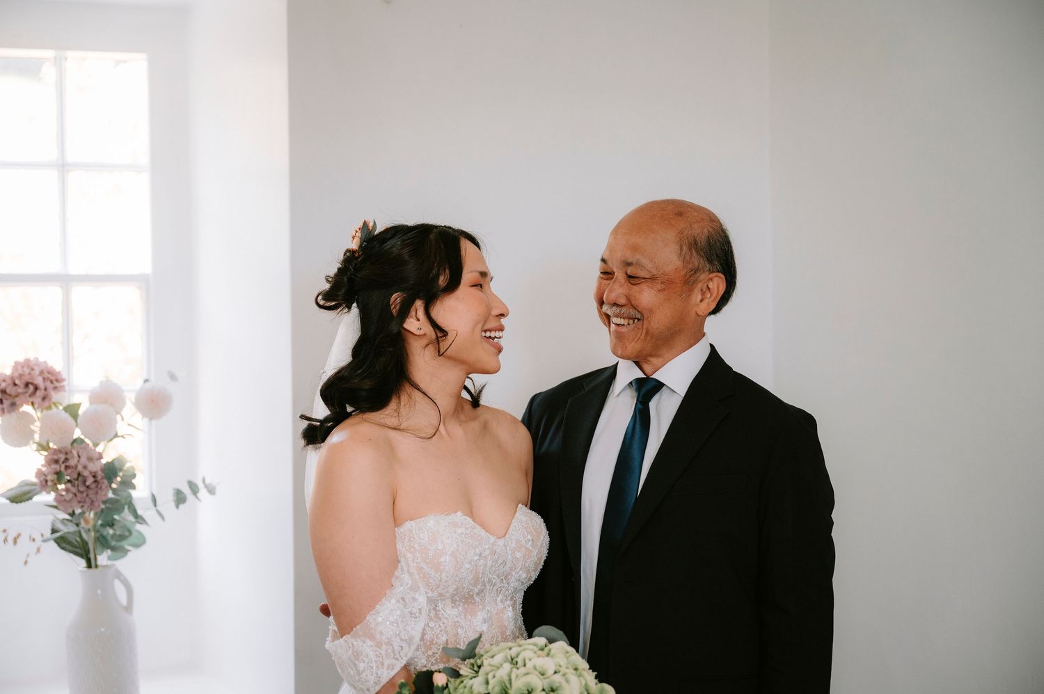 Tender wedding moment captured in a bright white room with natural window light.
