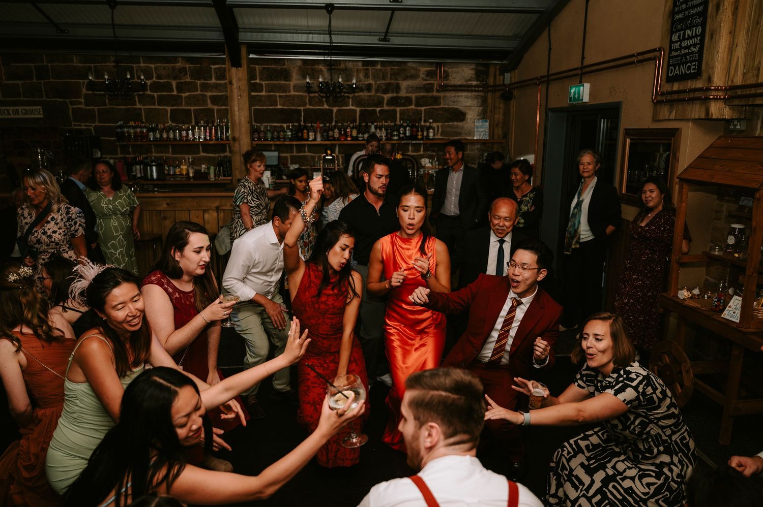 Energetic dance floor scene at wedding reception with guests in colorful attire.