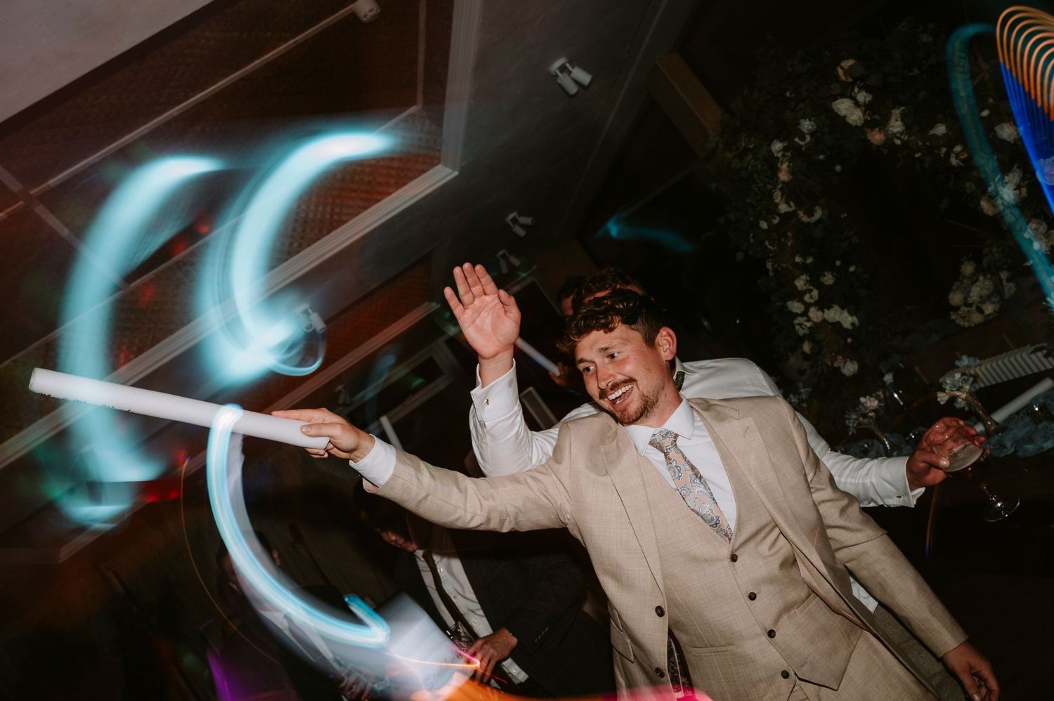 Dynamic dance floor moment with light painting effects at wedding reception.
