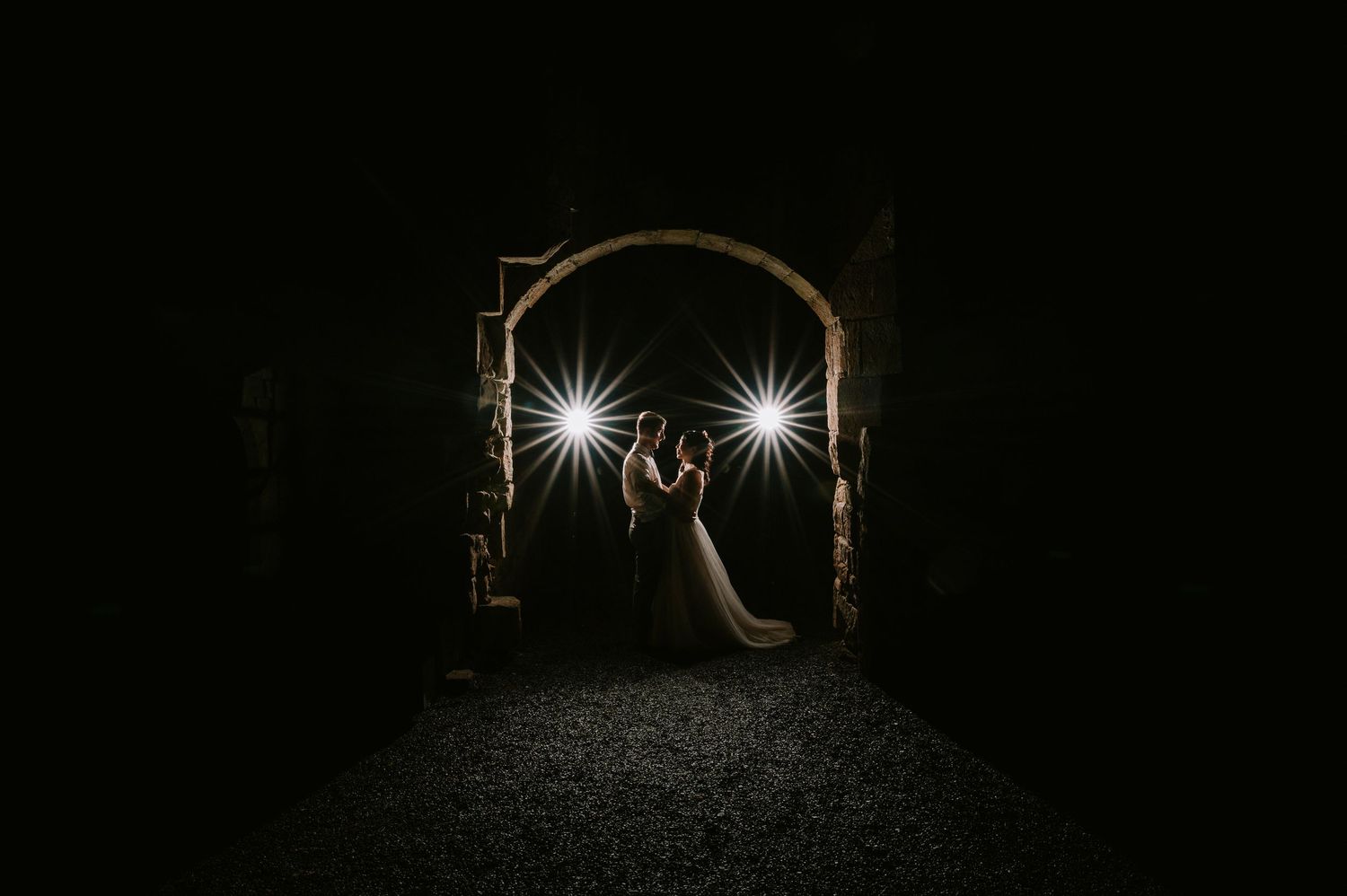 Dark tunnel archway illuminated by two bright lights creating a mysterious and atmospheric nighttime scene.