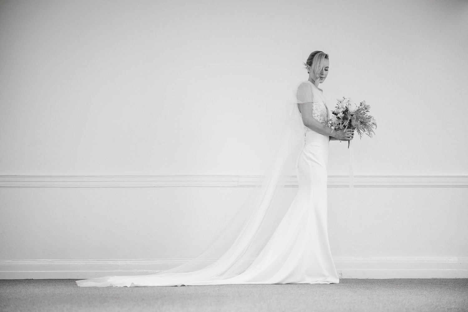 Classic black and white wedding photography in minimalist white room setting.
