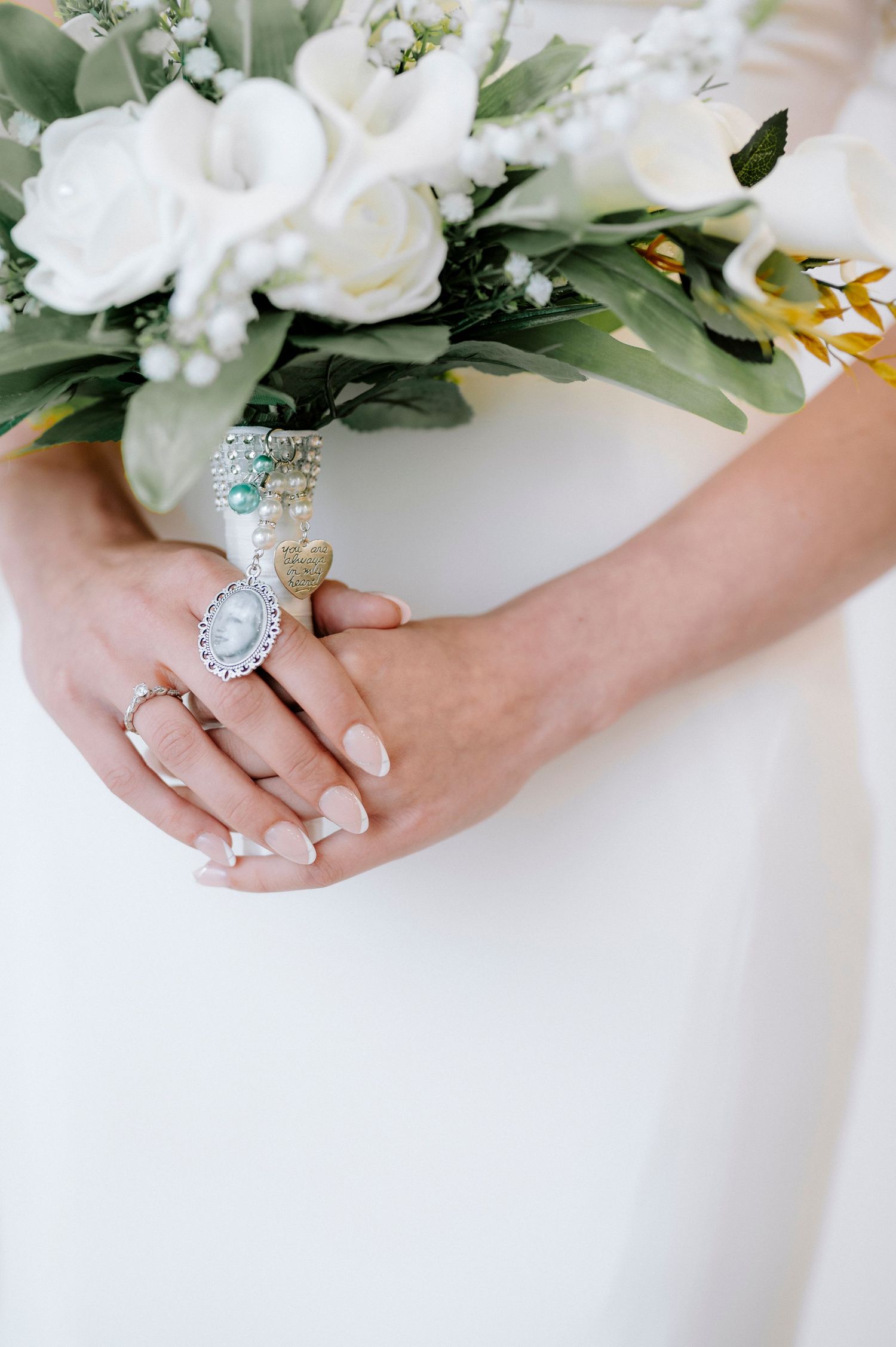 Close up of bridal jewelry and white floral bouquet details.
