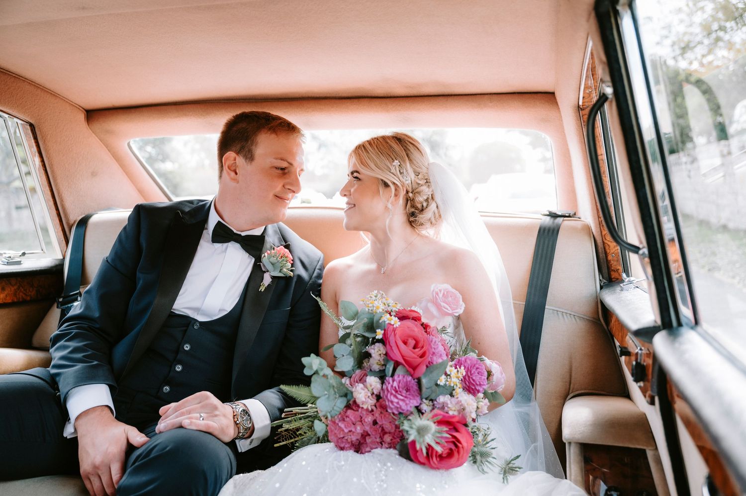 Candid wedding moment captured inside vintage car interior.
