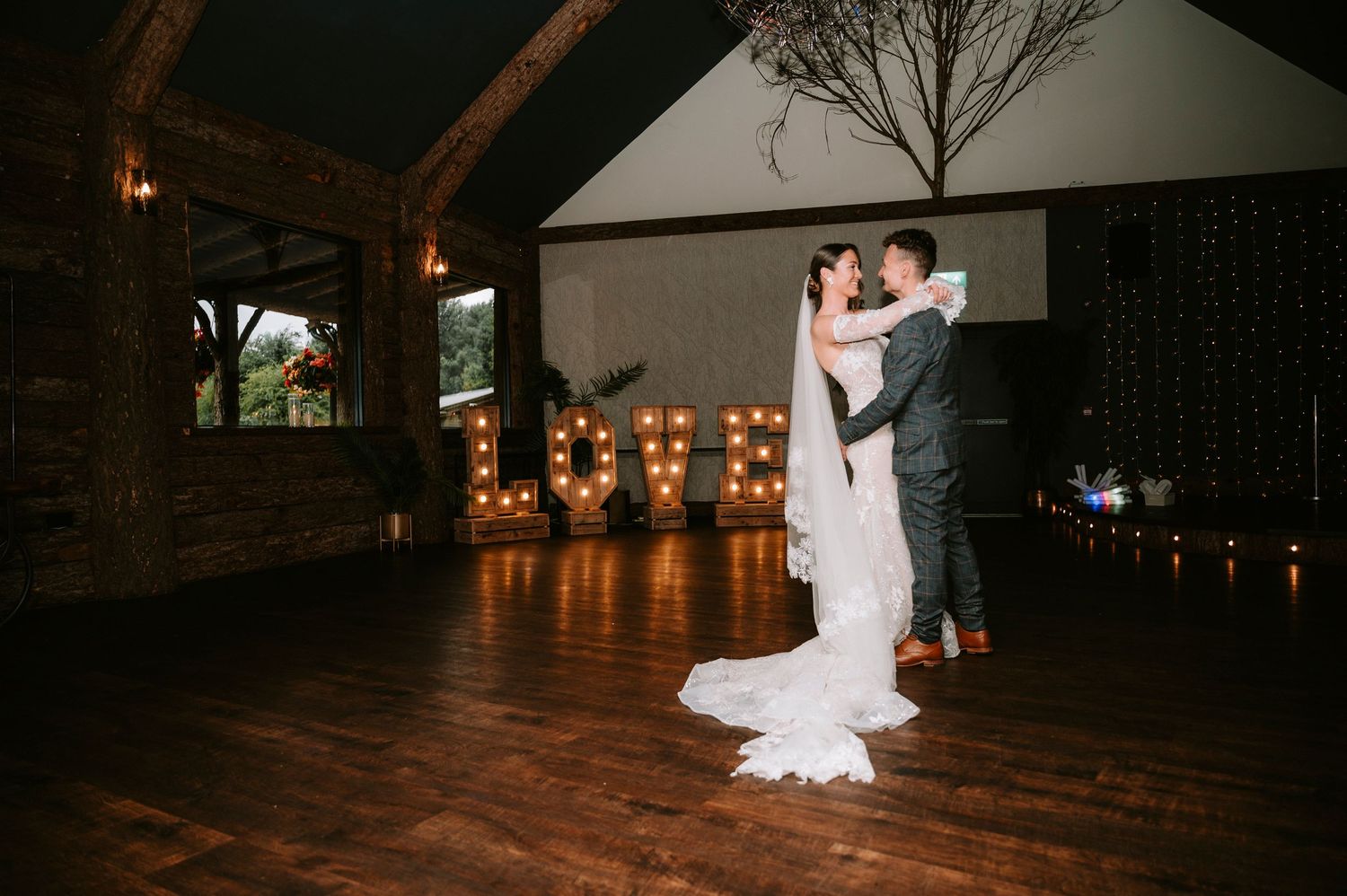 Newlyweds share their first dance in front of illuminated LOVE letters at their reception venue.