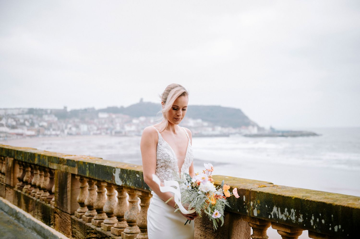 Scenic coastal wedding venue with stone balustrade overlooking the ocean on an overcast day.