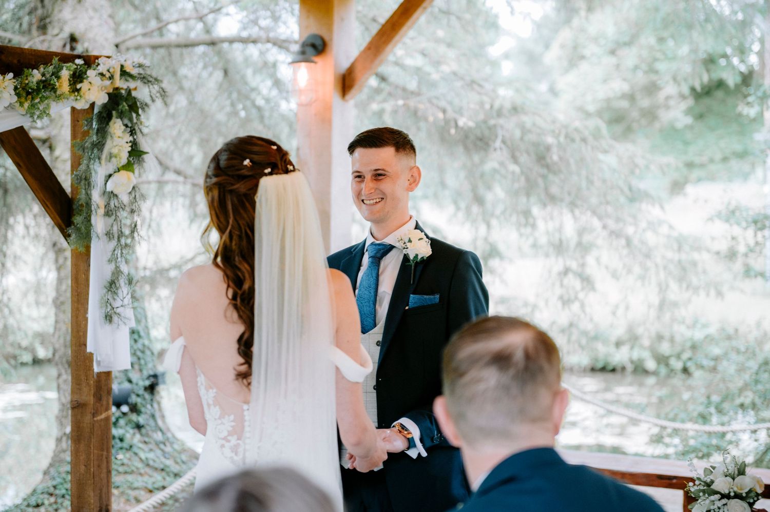 Wedding ceremony in a rustic covered pavilion with string lights and natural lighting.