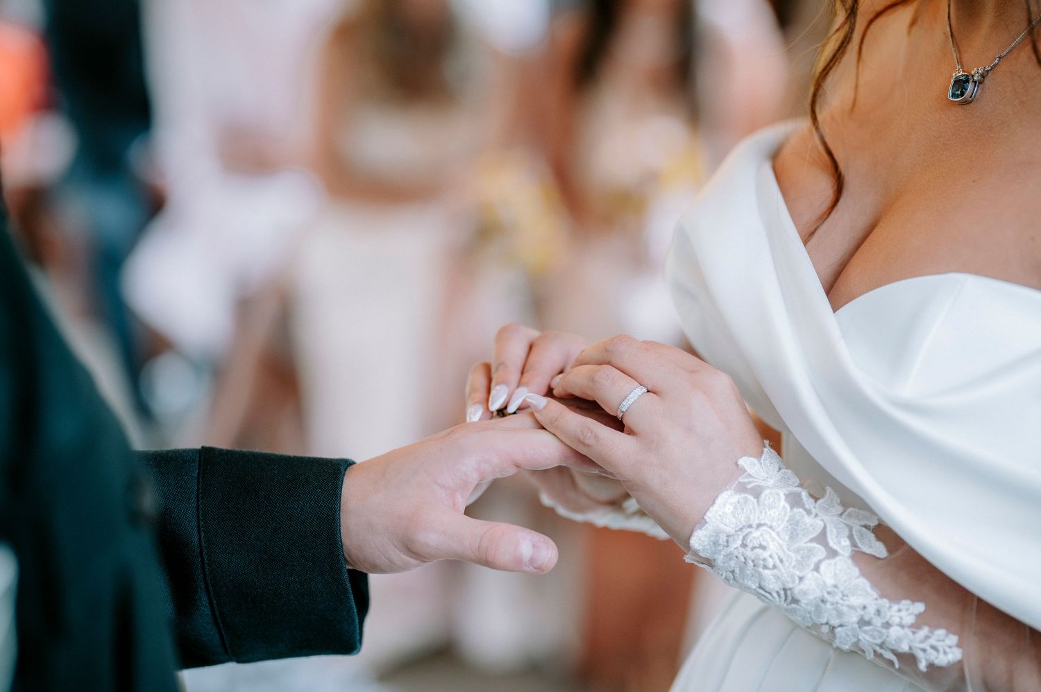 Close-up details of wedding rings being exchanged during an intimate ceremony moment.