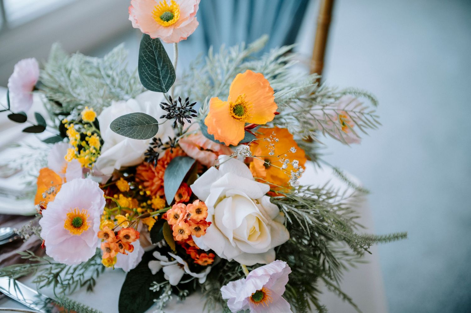 Colorful floral arrangement featuring orange, pink and white blooms with greenery.